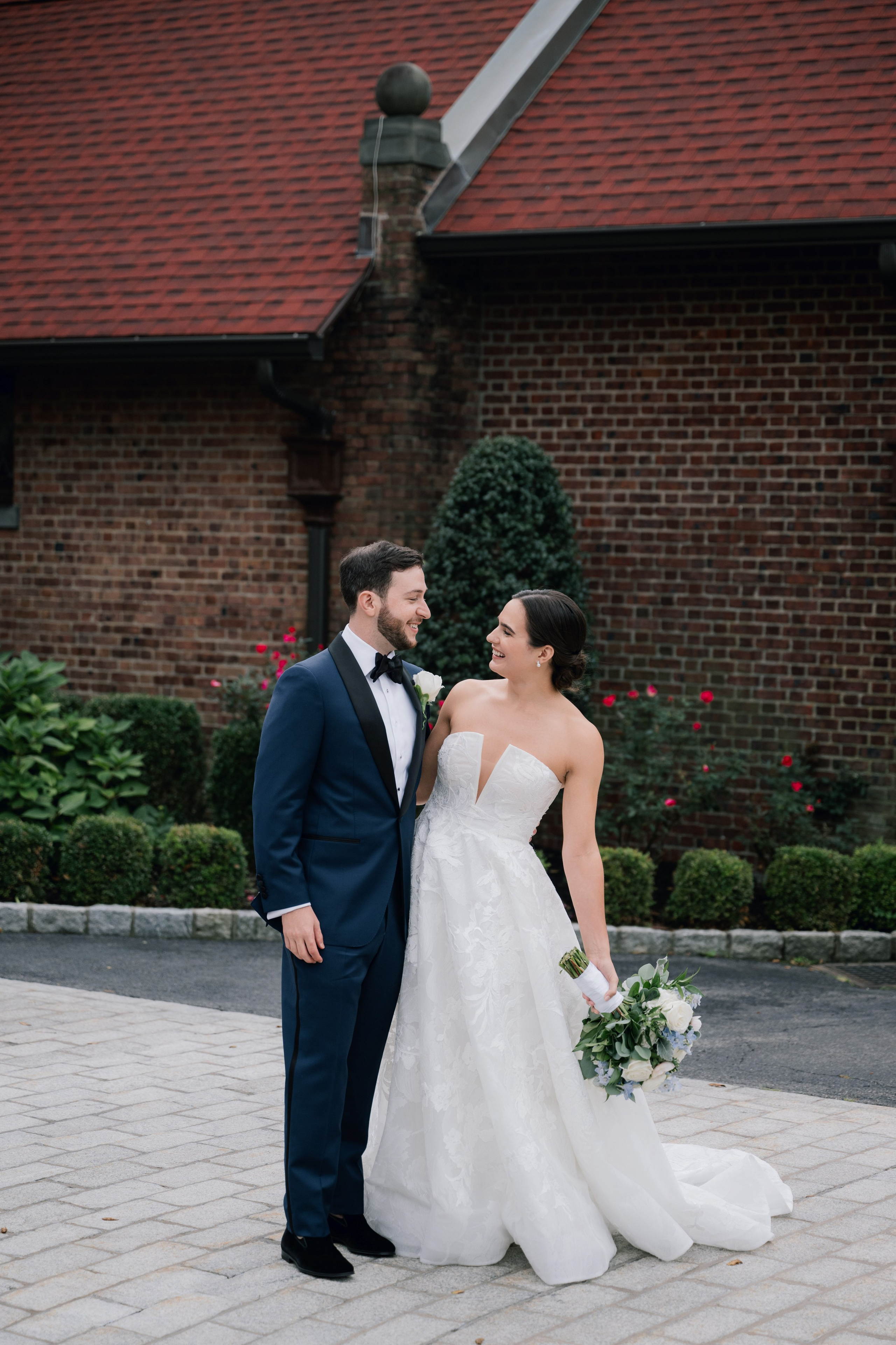a bride and groom pose for a photo in front of the red brick building