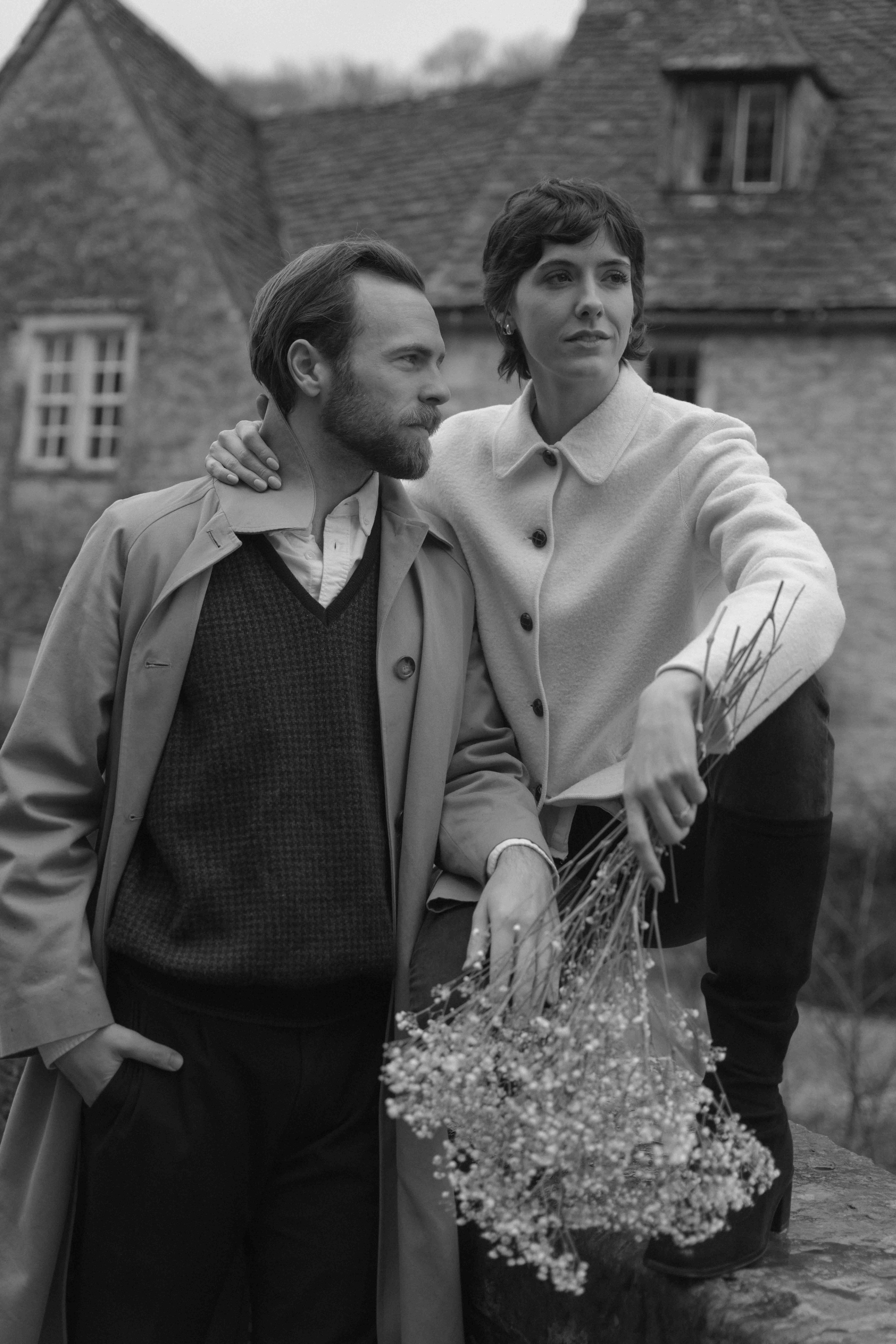romantic candid couple moment in rain holding flowers during engagement photoshoot in Castle Combe
