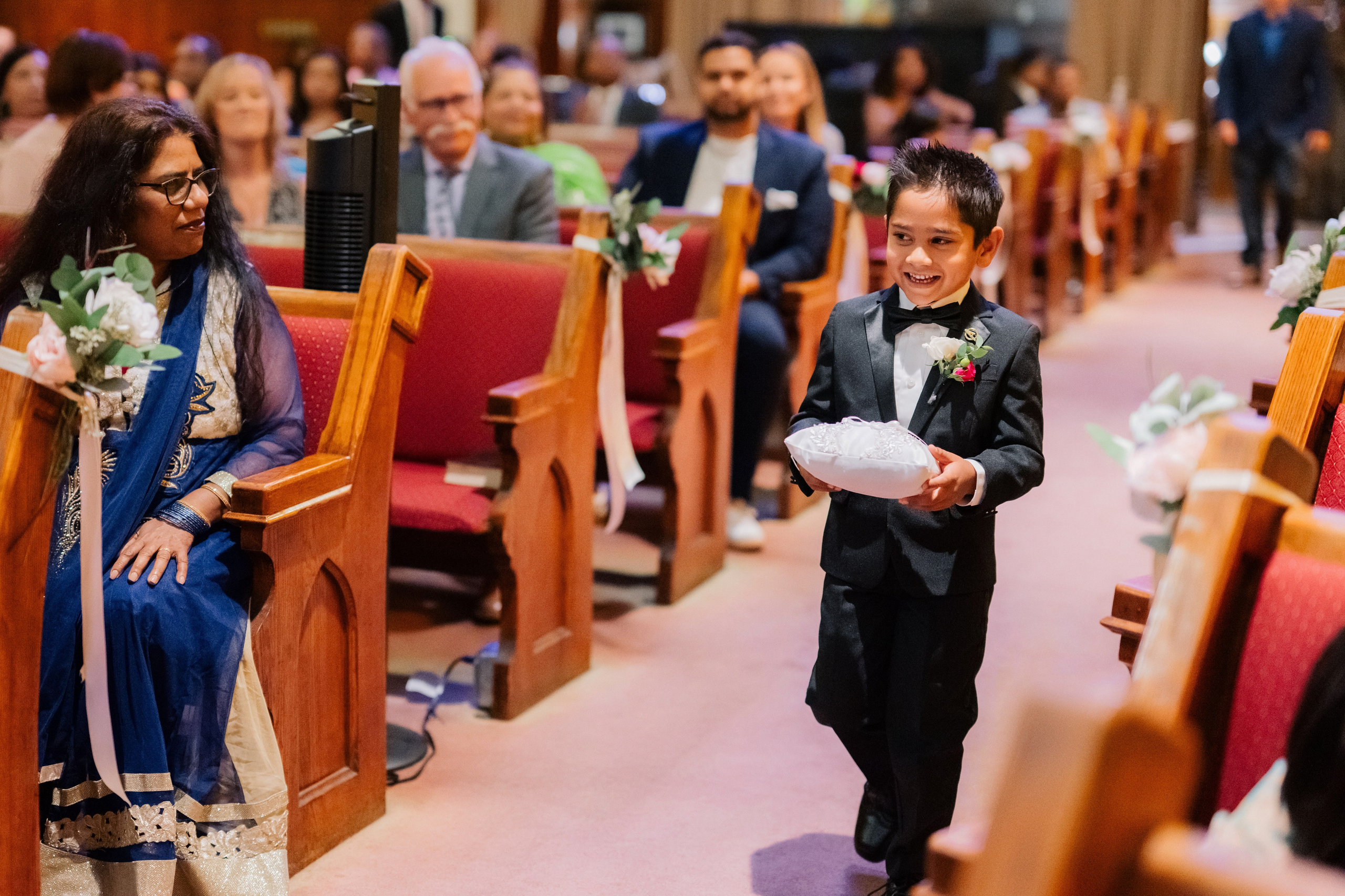 a young boy in a suit and tie is walking down the aisle