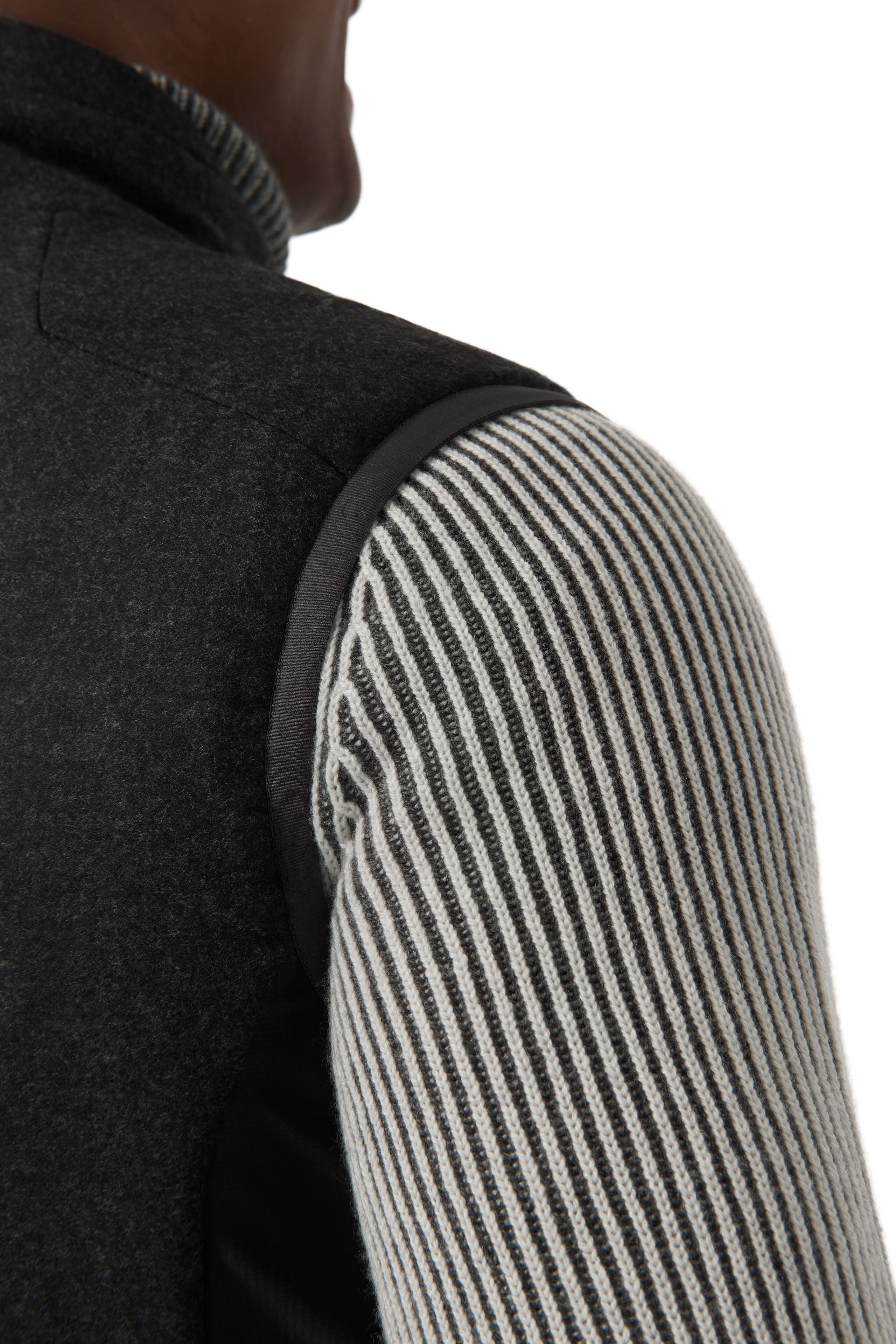 Detailaufnahme – Struktur des grauen Strickärmels und Übergang zur schwarzen Weste.