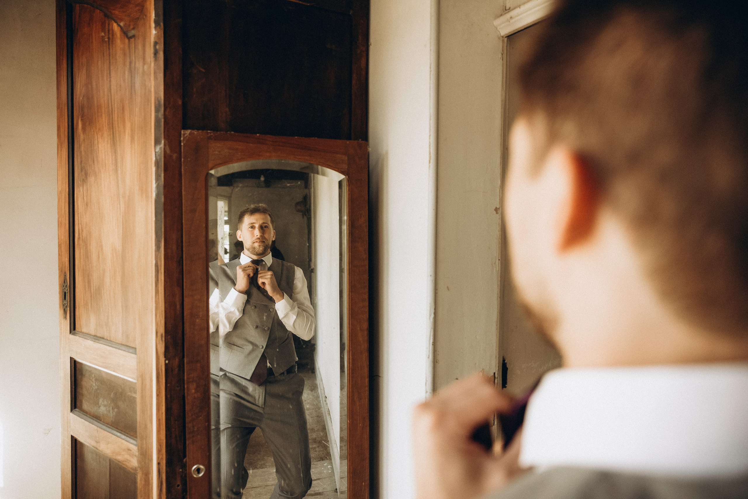 Happy groom getting ready for the wedding, looking in the mirror