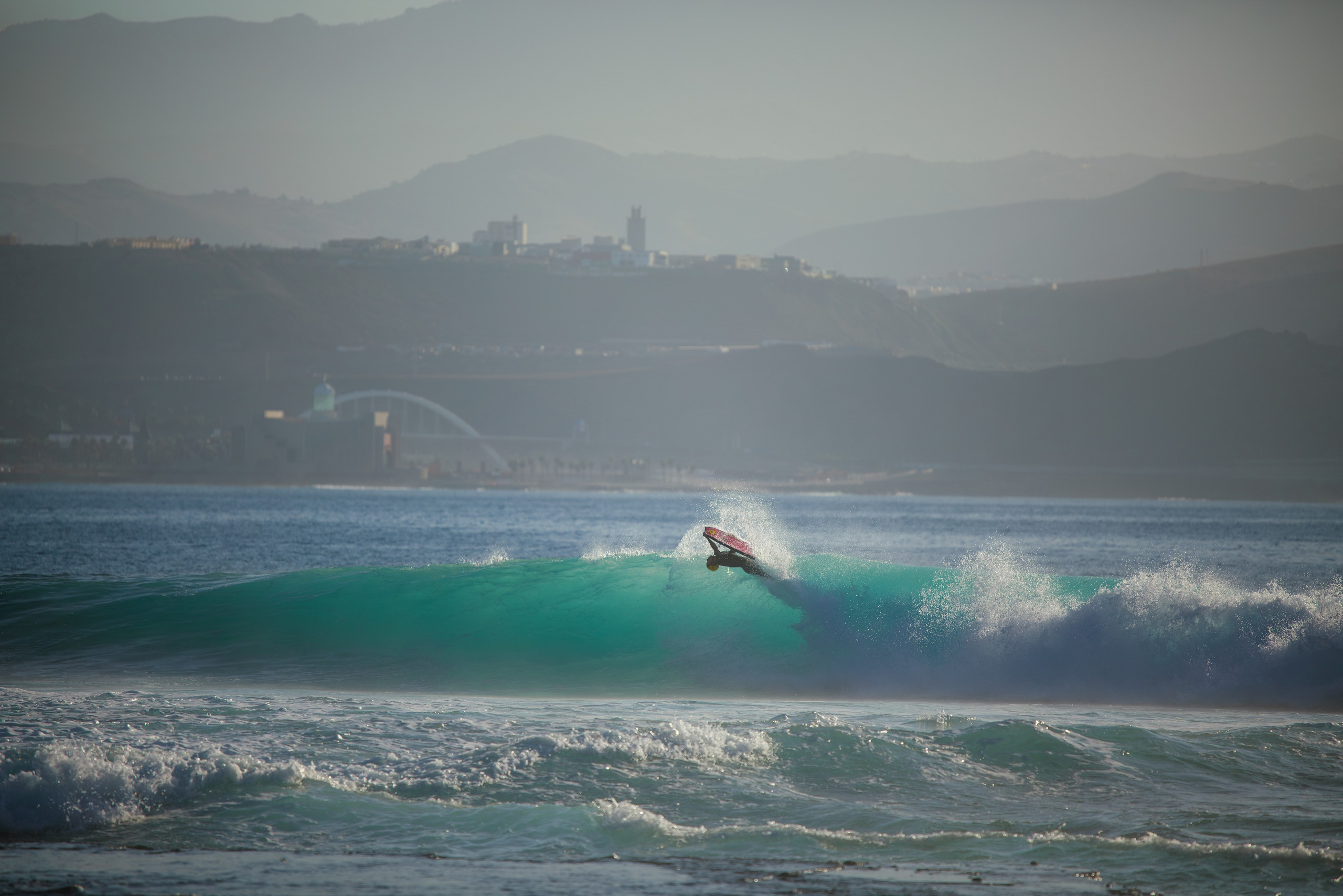 A morning at El Confital in Las Palmas. A clean set came in over the reef and this rider went upside down right off the lip, with spray everywhere and the whole city sitting quietly in the haze behind him.I shoot surf and sports in Gran Canaria. If you'd like photos of your session, feel free to message me.