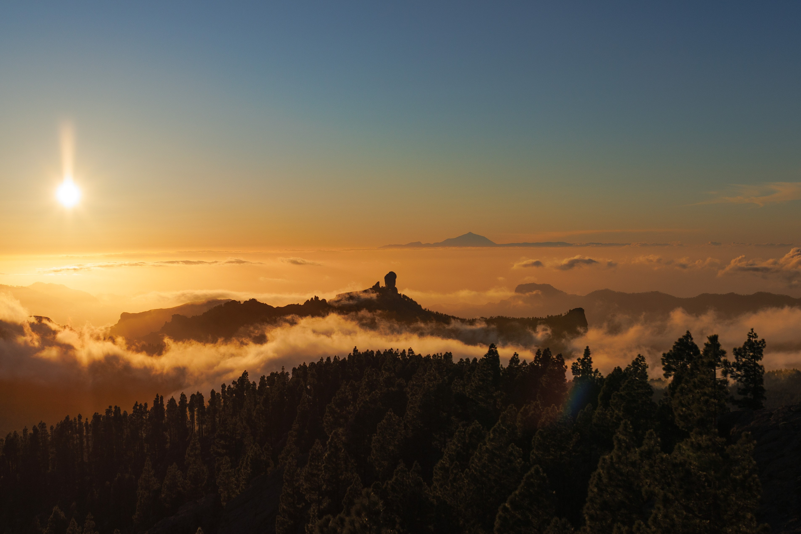 Sunset over a sea of clouds in the Gran Canaria mountains, with Mount Teide visible on the horizon
