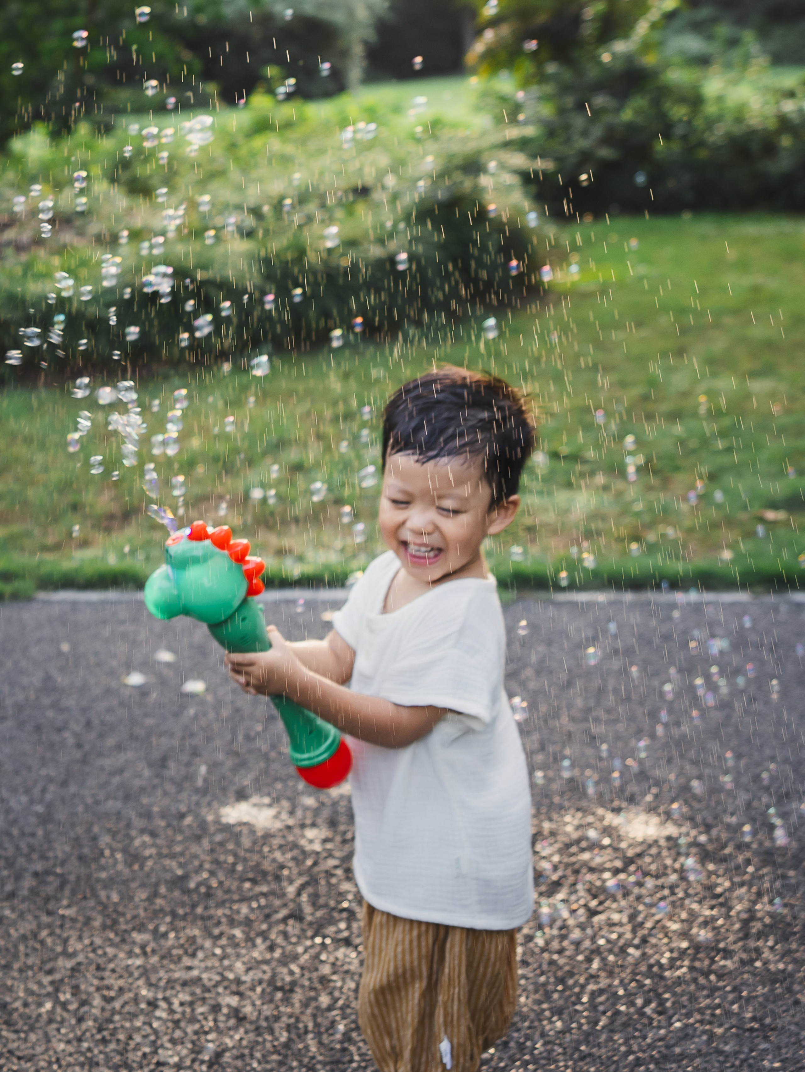 A young child reaches for bubbles in soft late afternoon light during a Shanghai lifestyle family photography session.