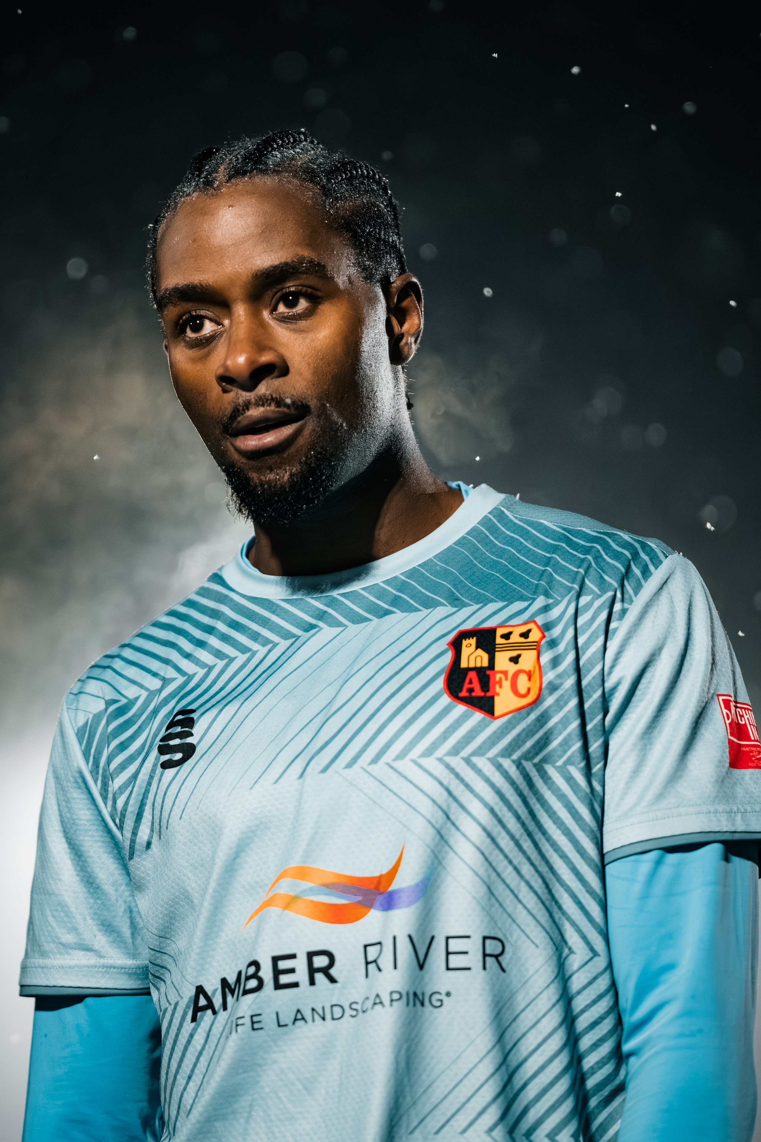 Editorial football portrait of a player in a light blue kit under stadium lighting, professional athlete photography.