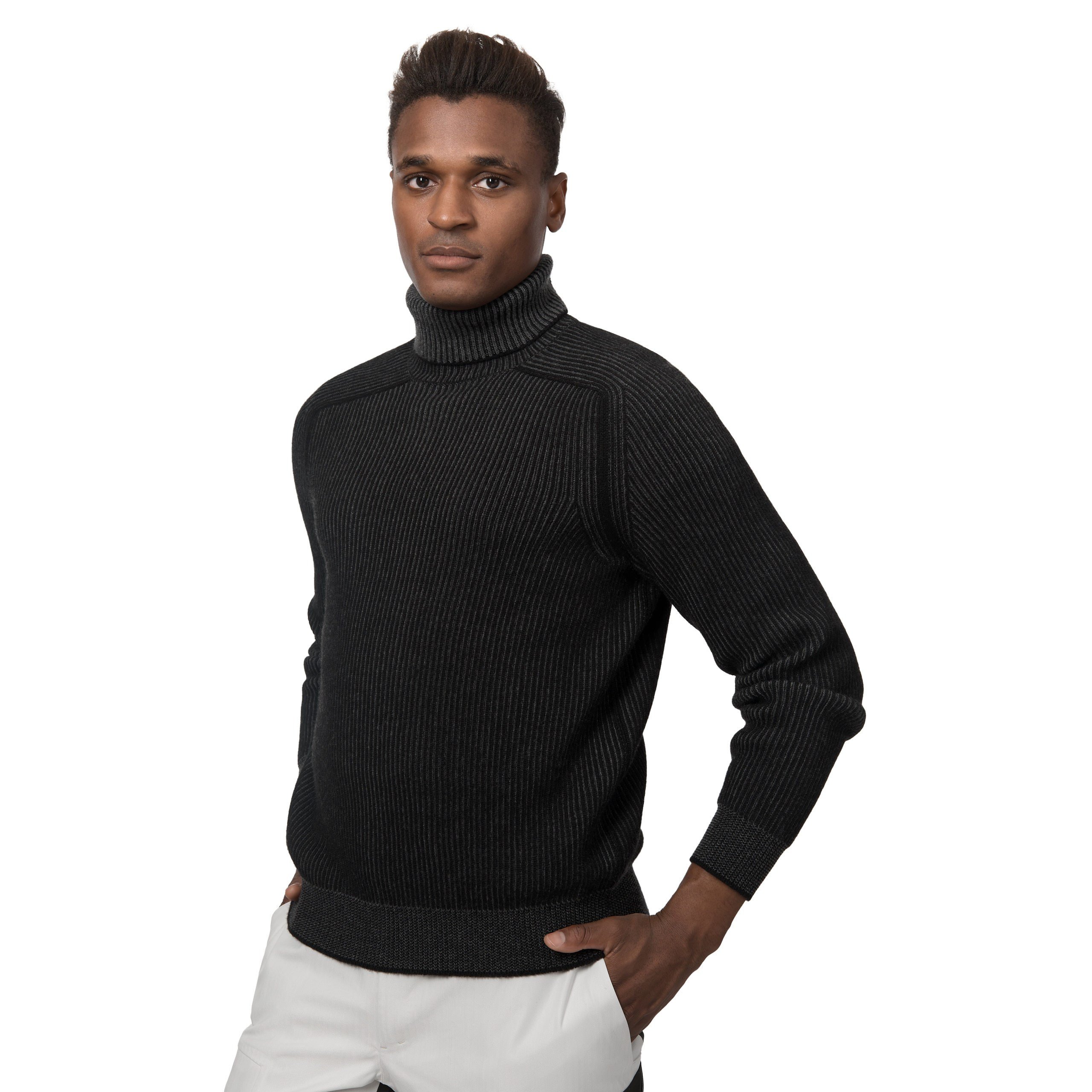 Model in schwarzem Rollkragenpullover, steht locker mit Hand an der Hüfte, Studioaufnahme.