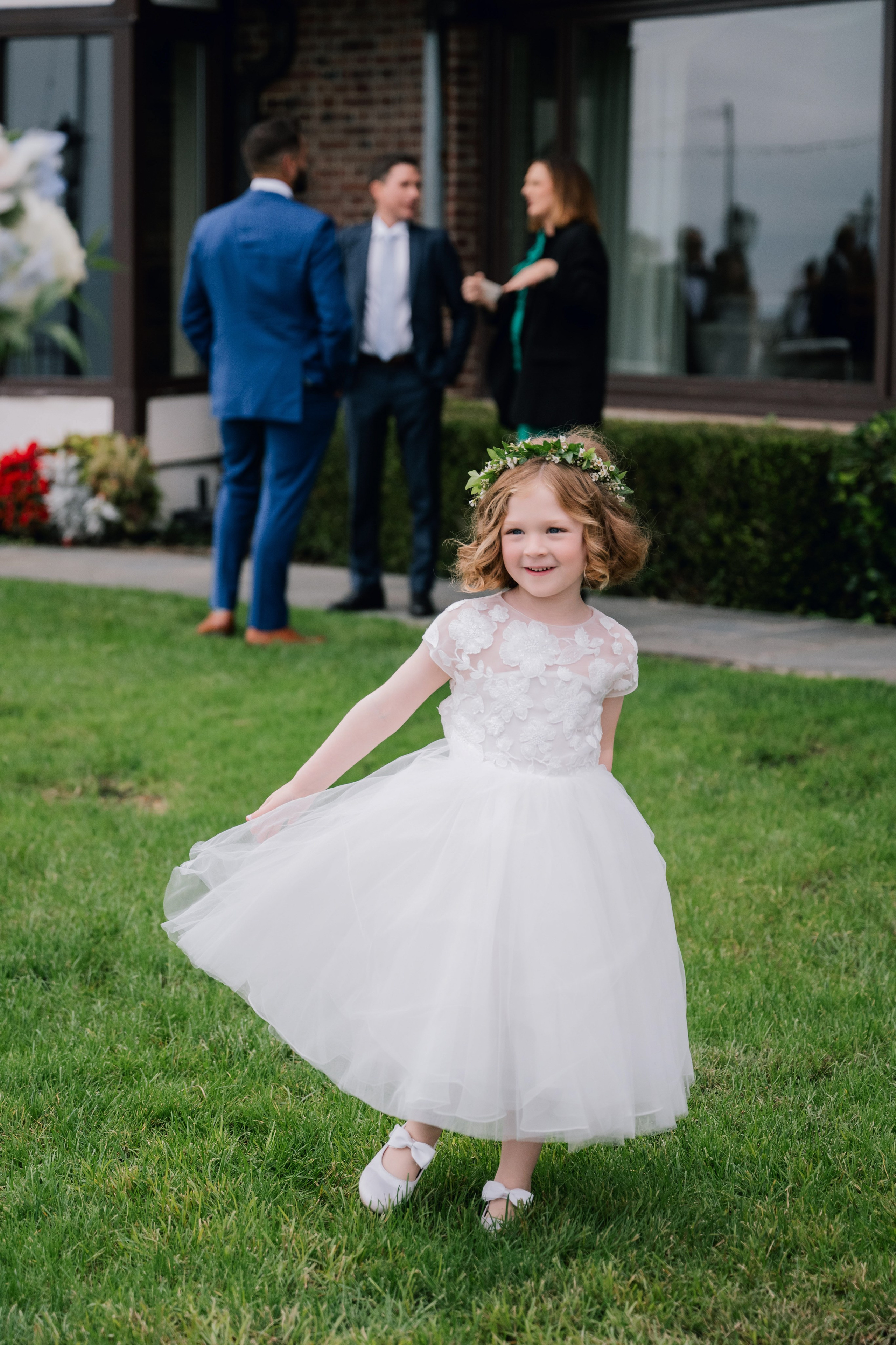 a little girl in a white dress and flower crown