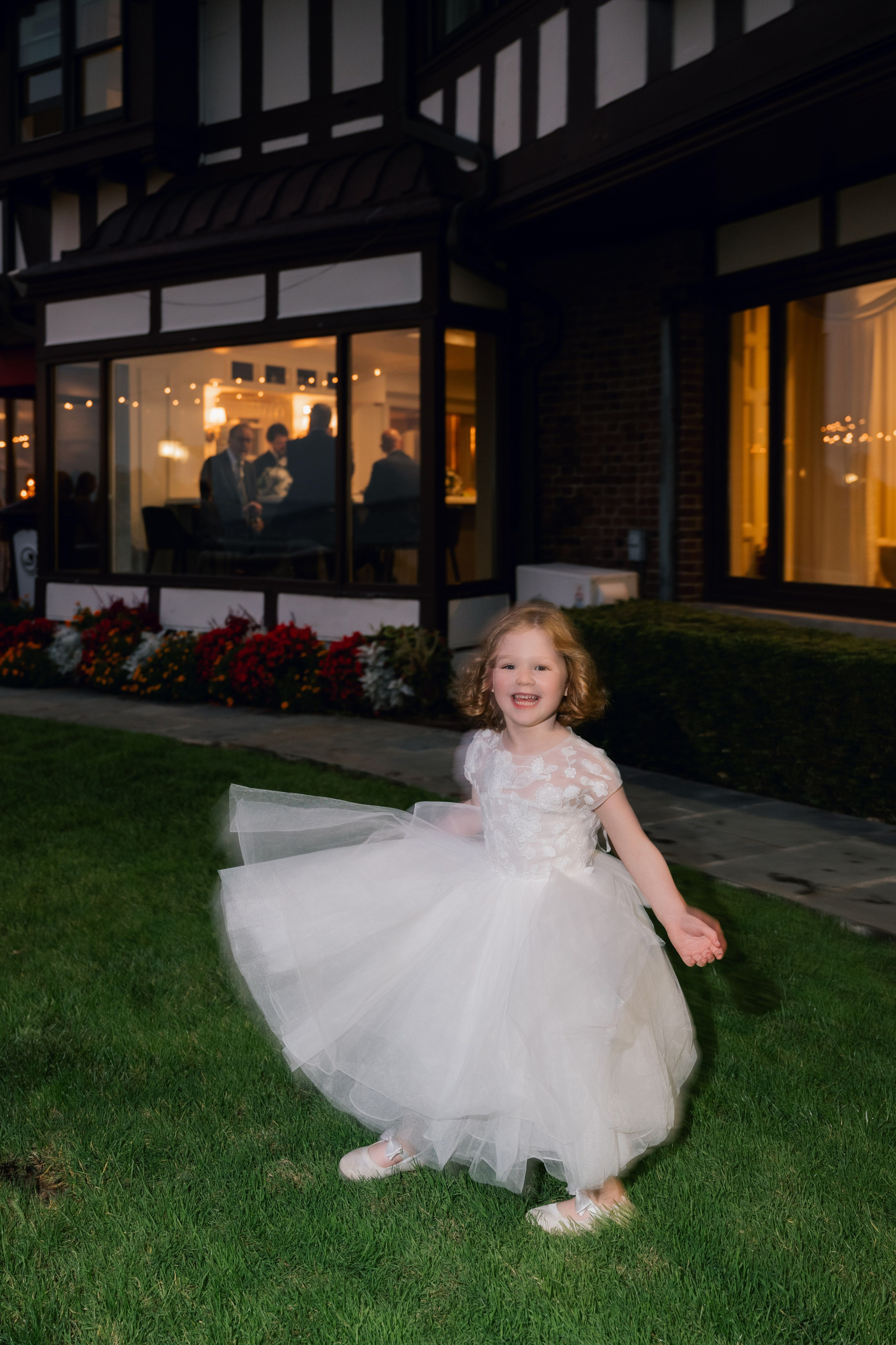 a little girl in a white dress is walking in the grass