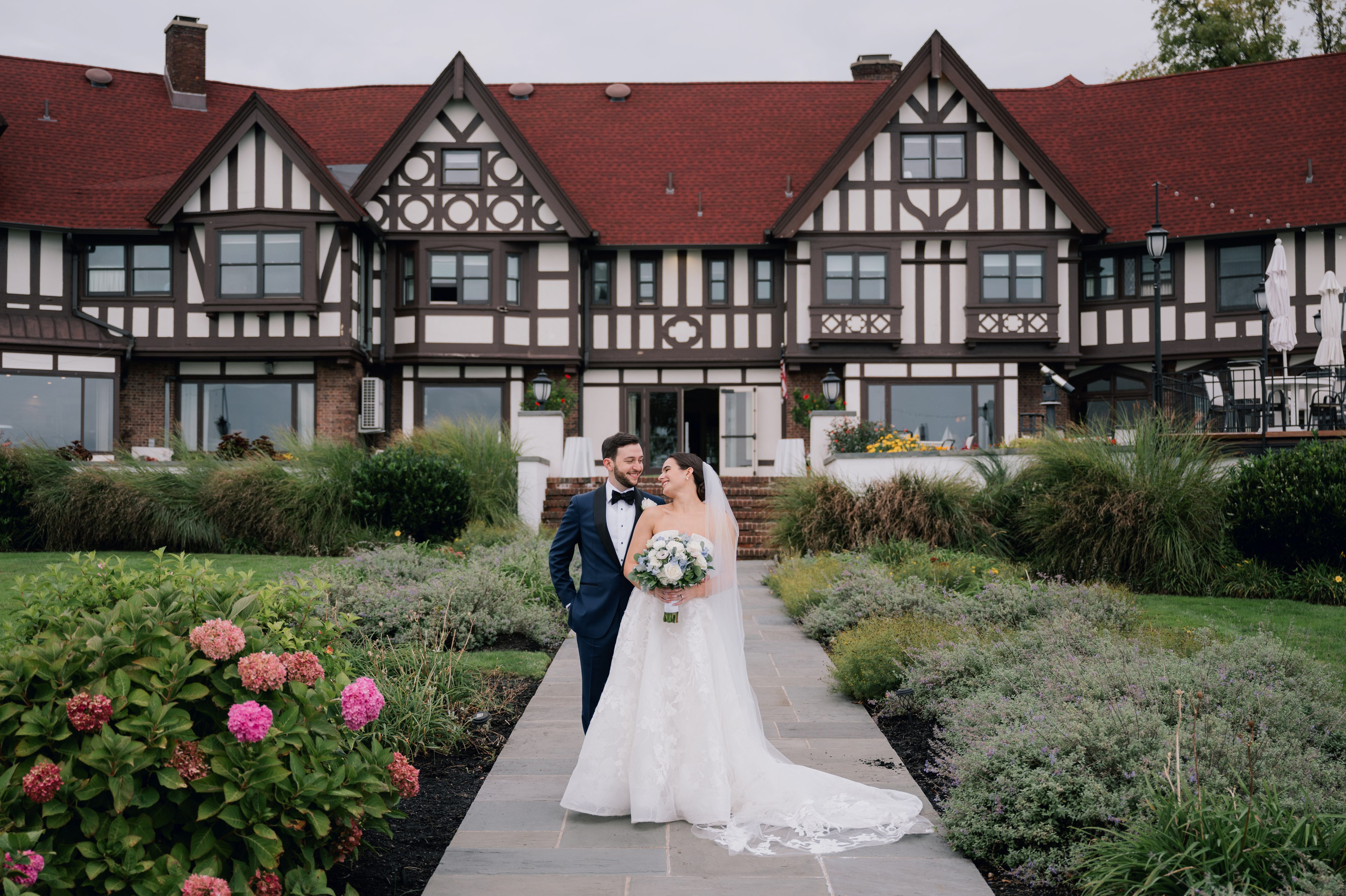 a bride and groom standing in front of a large house