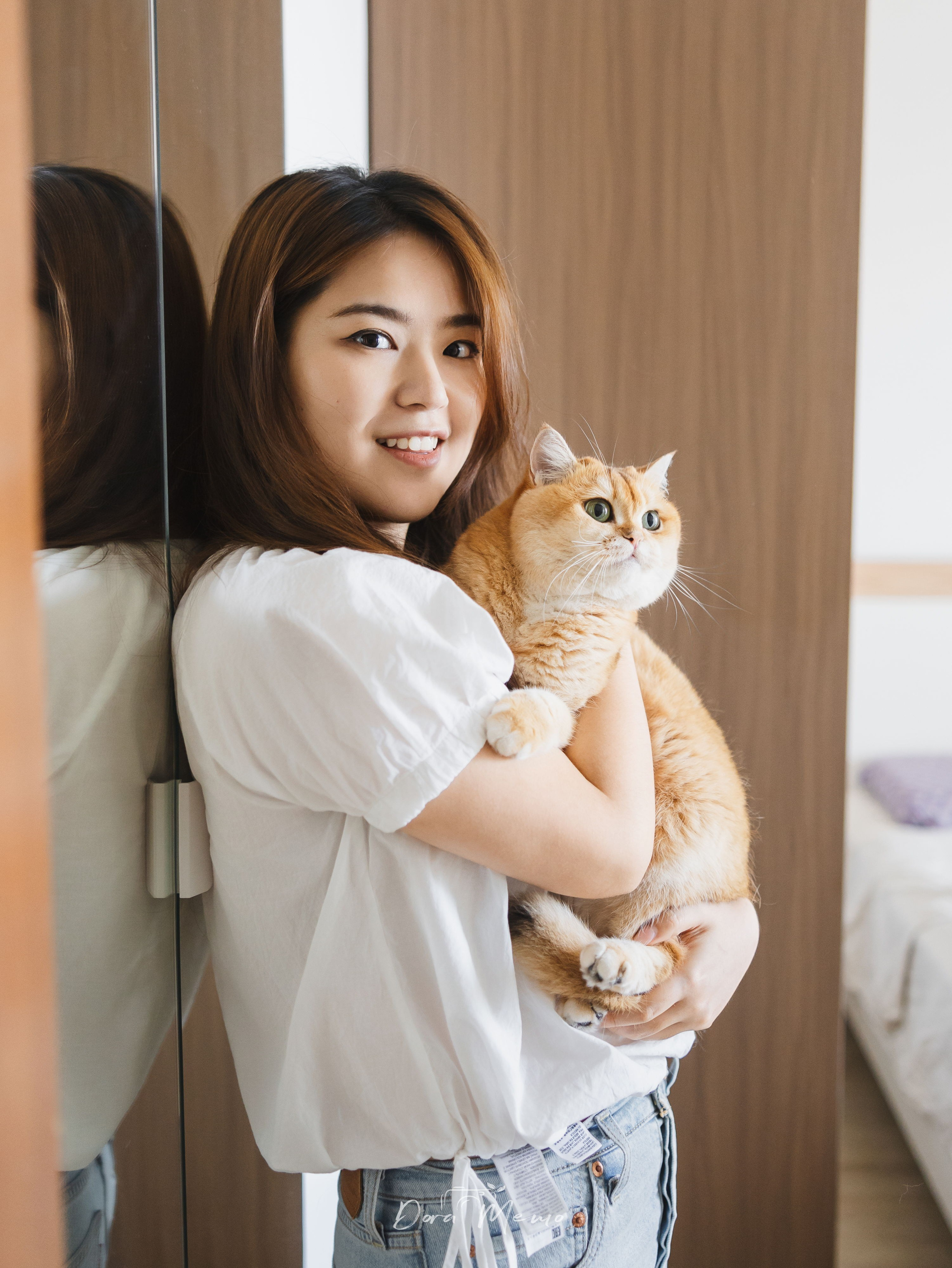 A woman holds her cat gently at home, creating a warm portrait for a pet family photo story.