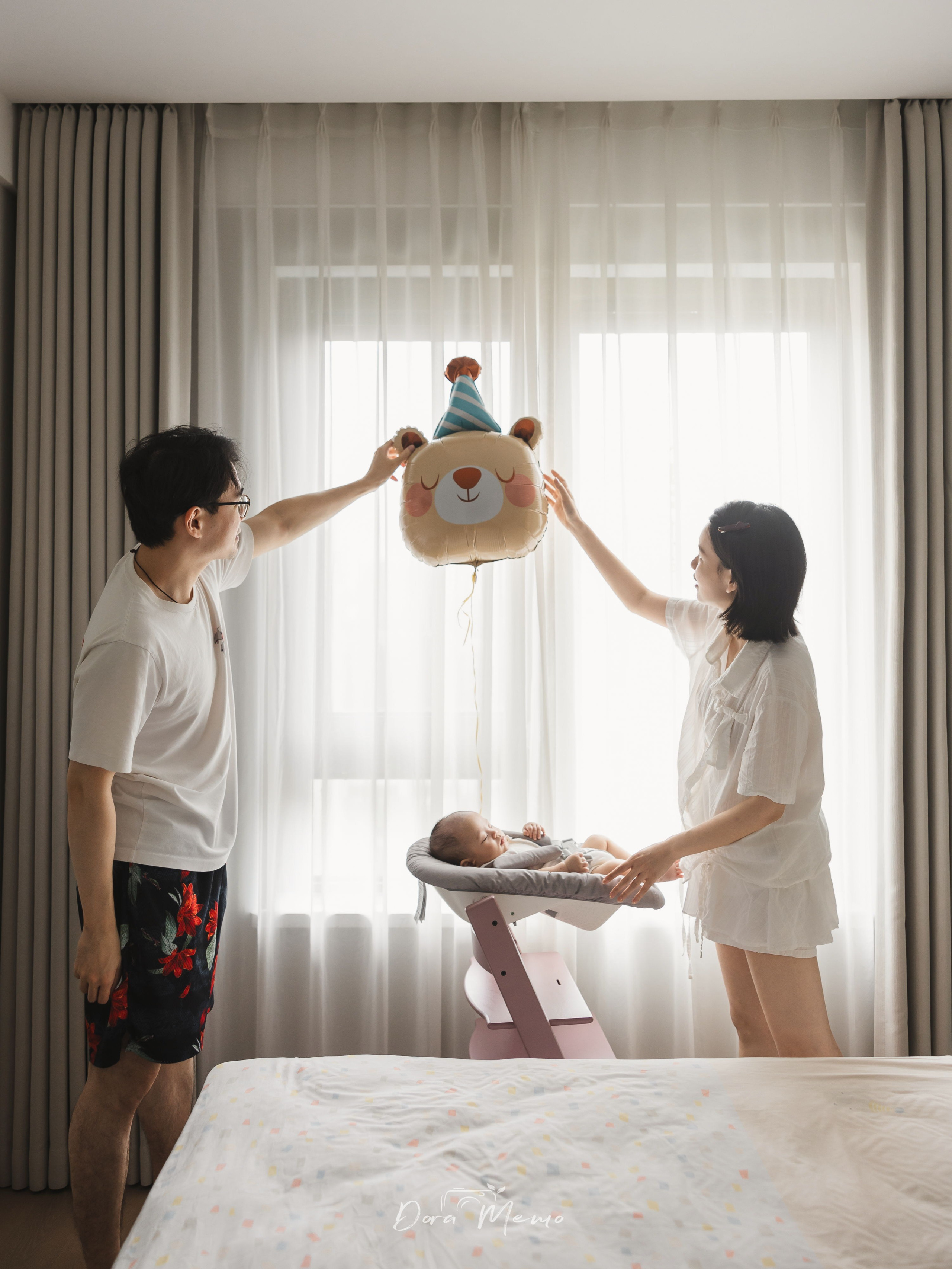 Shanghai family photography session at home with parents celebrating their baby's 100-day milestone by the window.