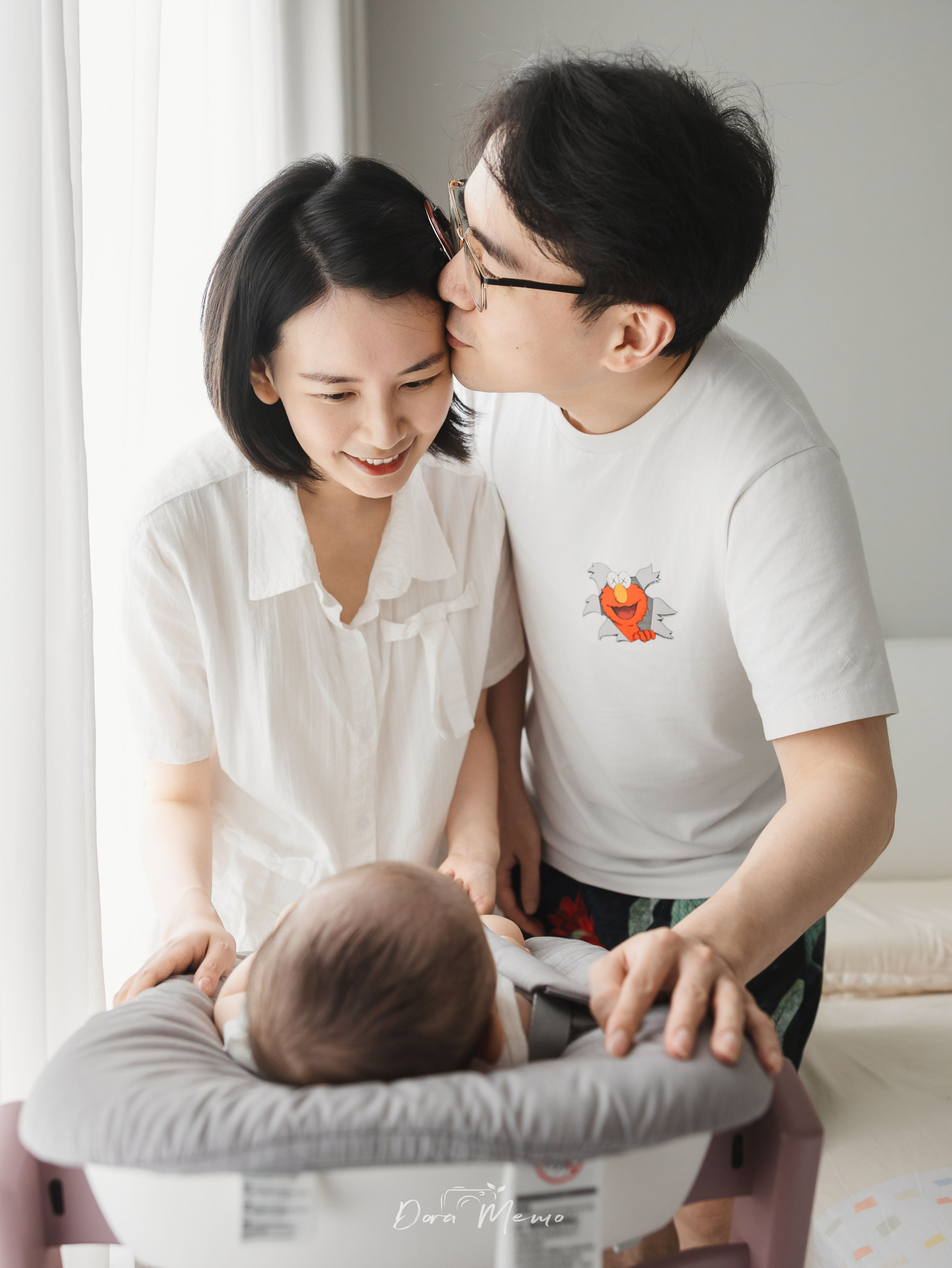 A warm family moment with parents kissing above their baby during an at-home Shanghai lifestyle photography session.