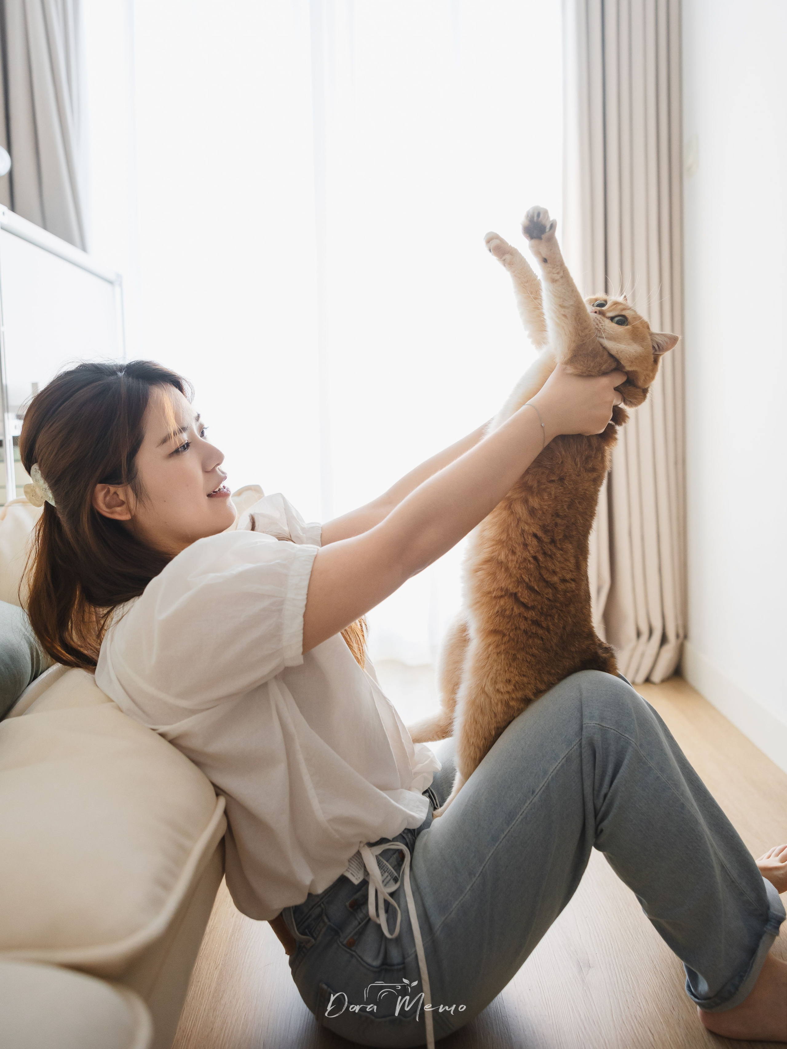 A playful moment between a woman and her cat during an at-home pet family photography session.