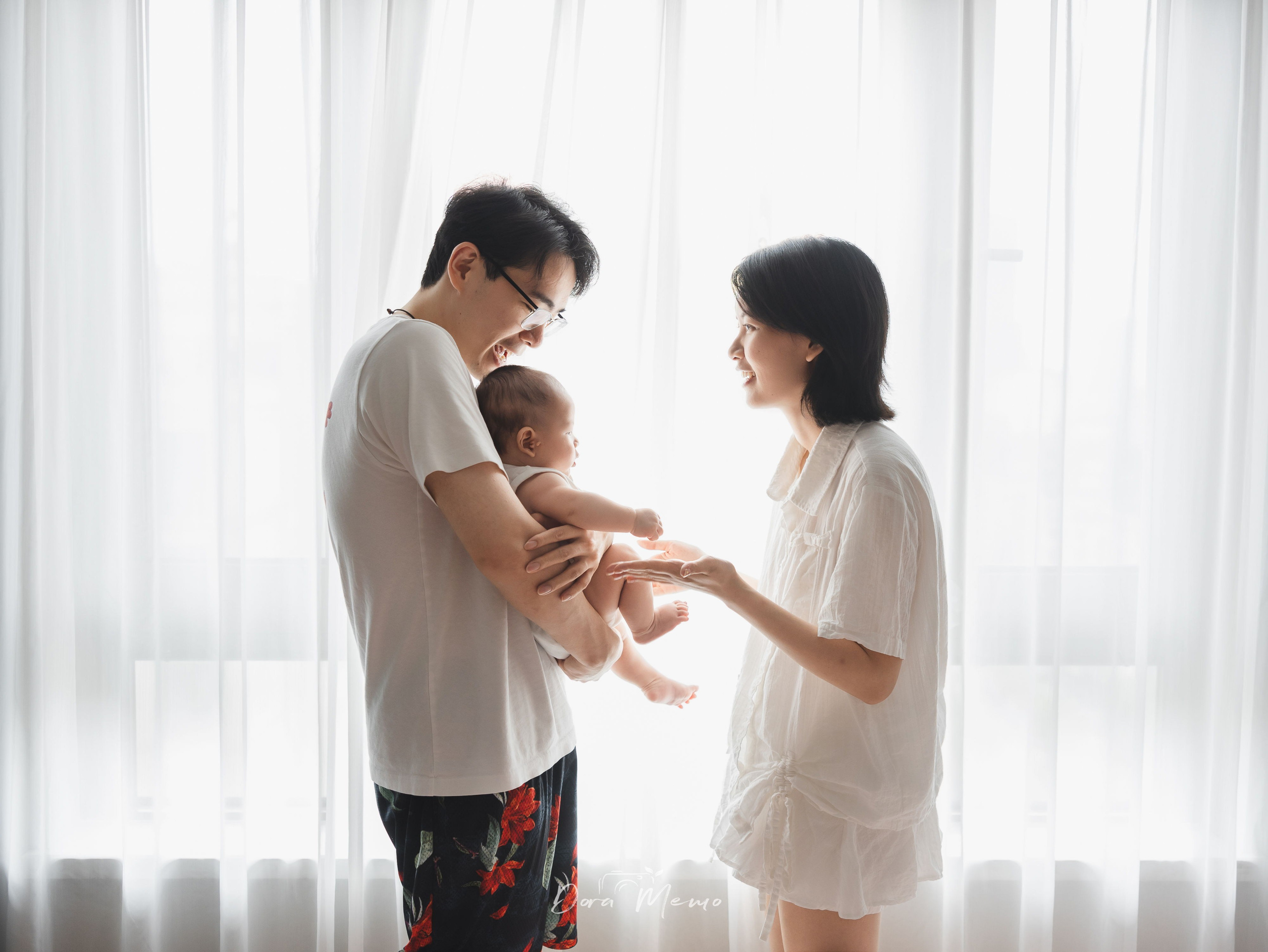 Shanghai family photographer capturing parents holding their baby together in gentle window light.