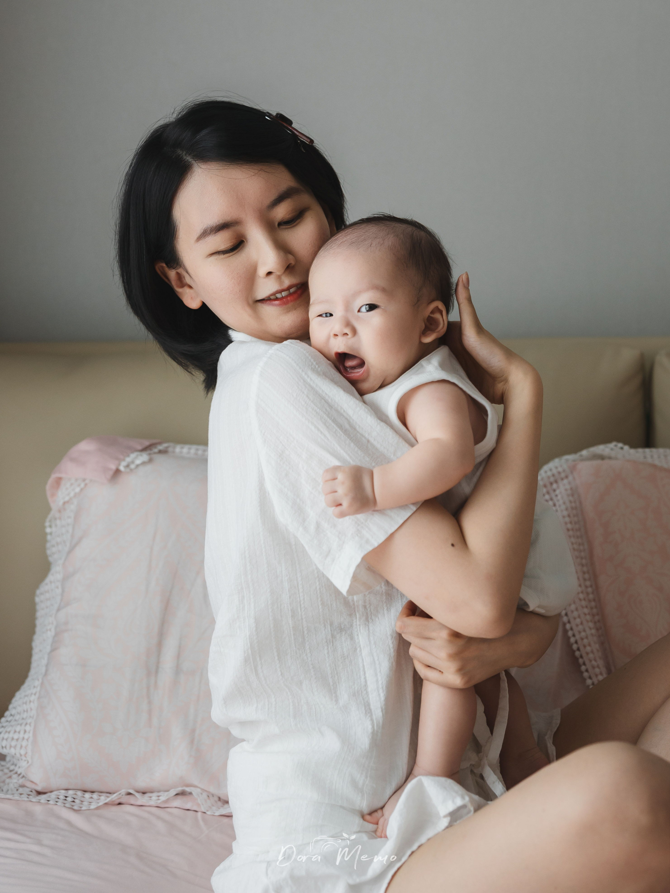 Mother holding her 100-day-old baby in a quiet, natural family portrait at home.
