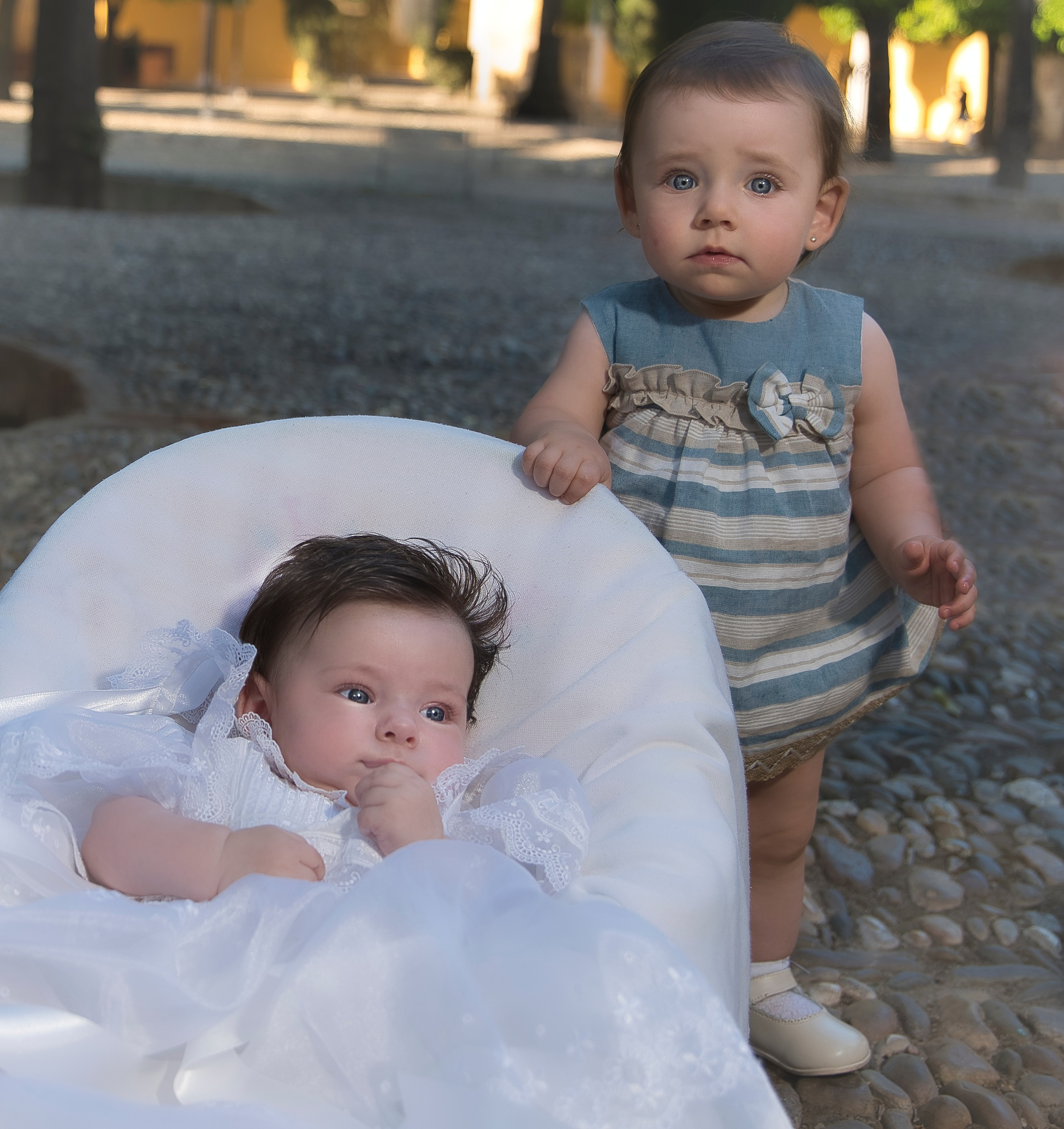 Niña vestida con traje de bautizo blanco, sostenida por sus padres en la iglesia.