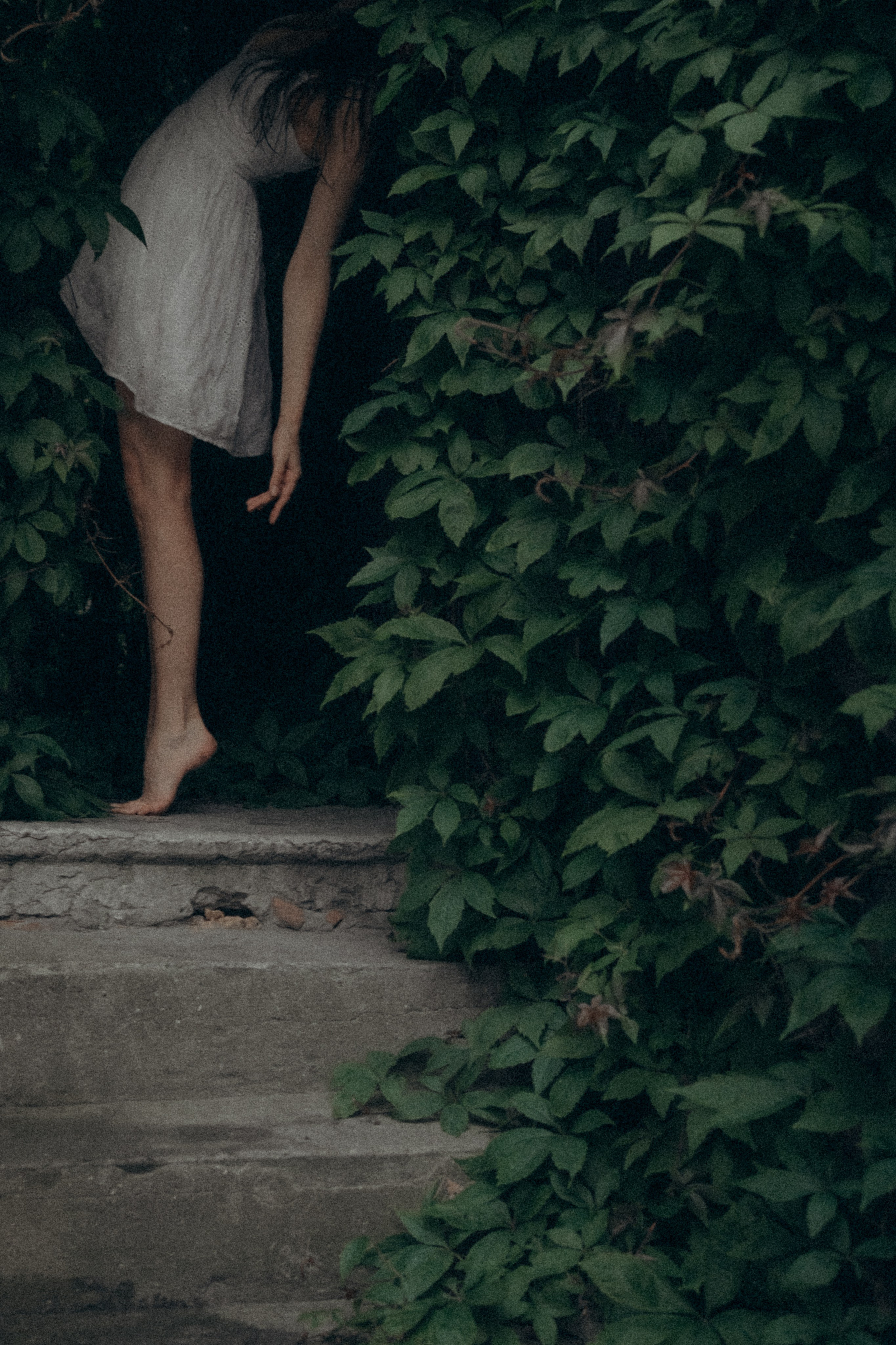 Fine art portrait of a woman stepping down stone stairs, surrounded by foliage, Estonia