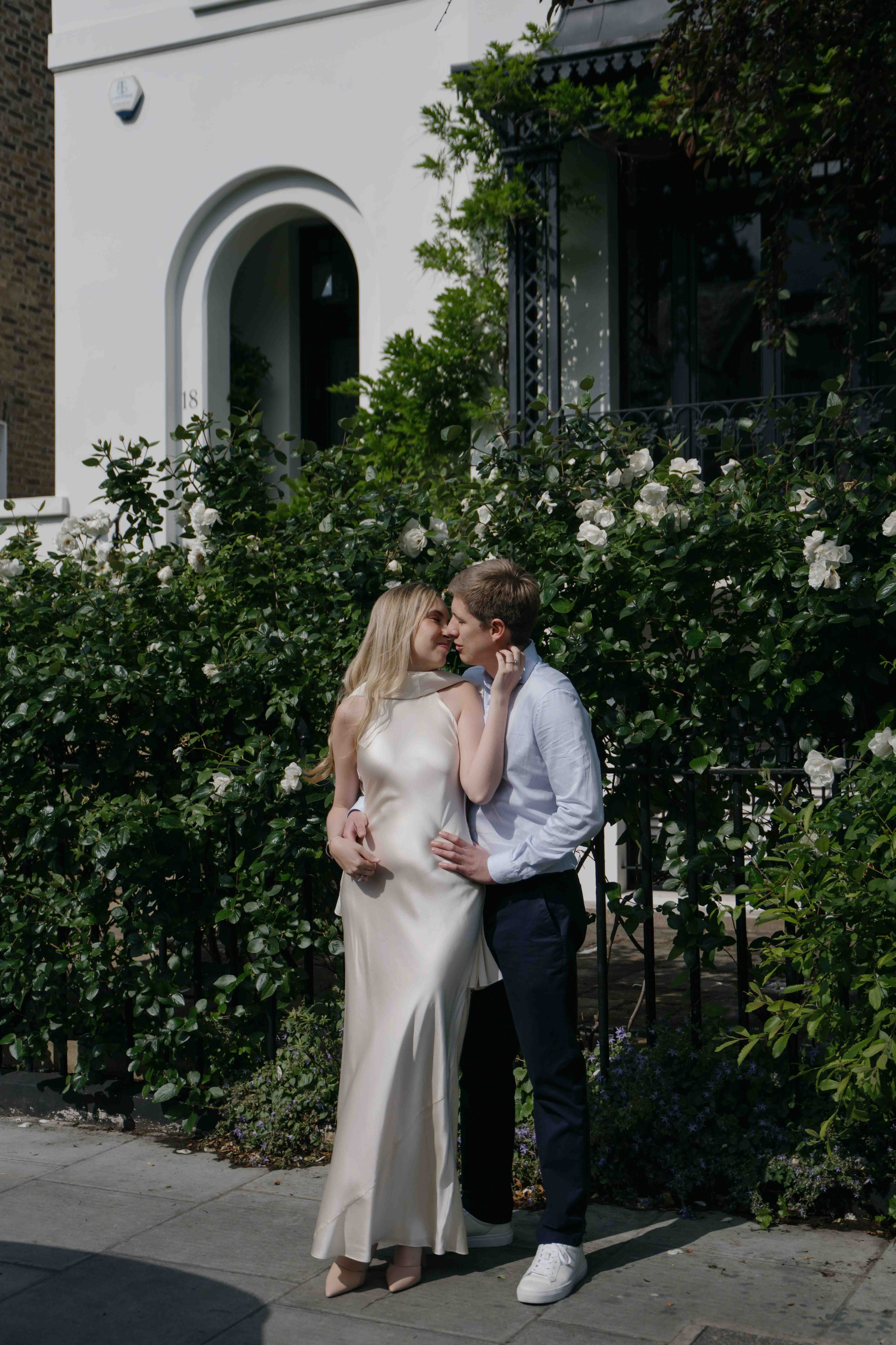 Romantic couple kissing surrounded by flowers in South Kensington London engagement session