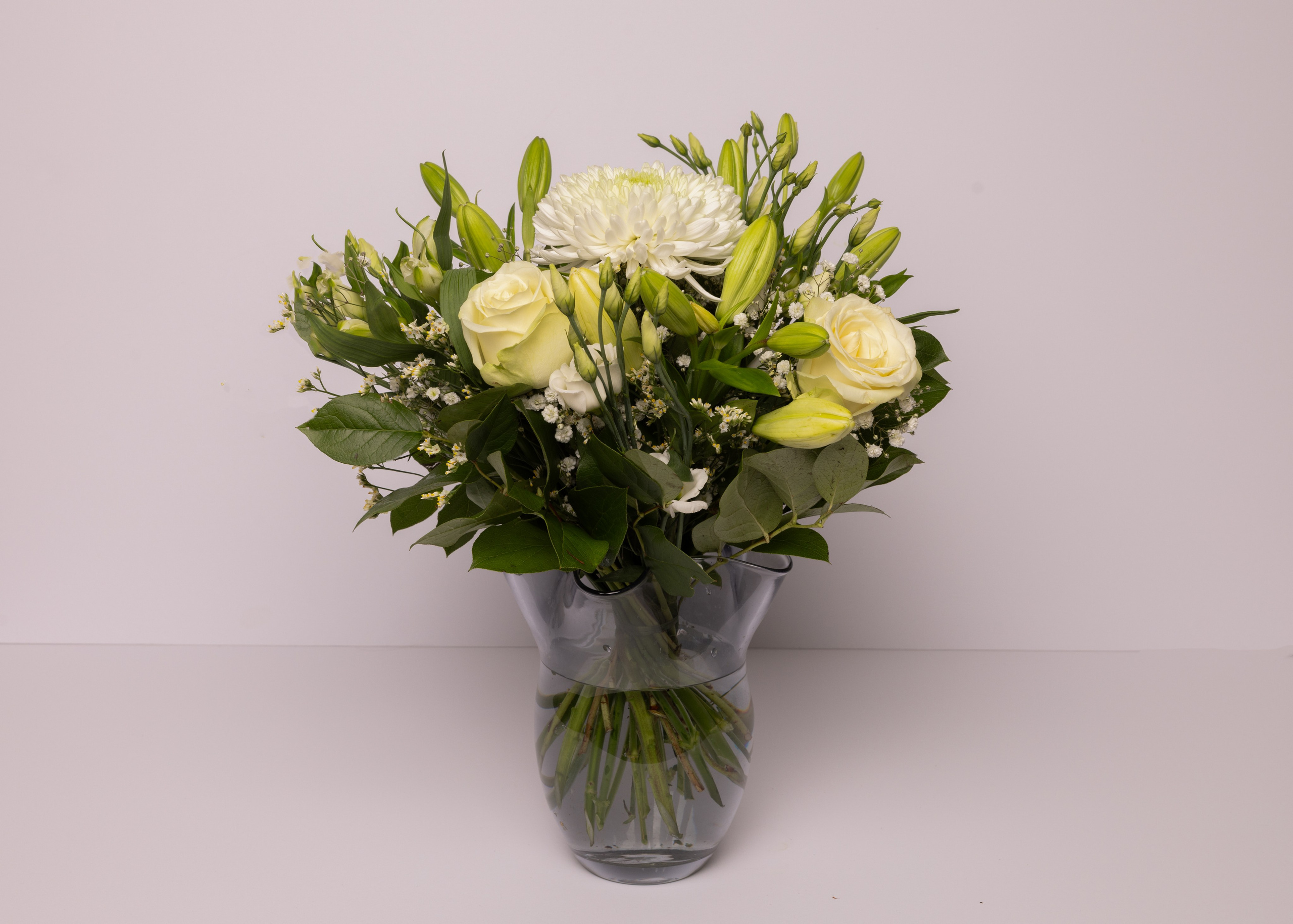 En hvid buket med grønne nuancer. Hvis du har nogle specifikke ønsker til farve, bedes du skrive en kommentar - så gør vi vores bedste. Alle vores buketter laves ud fra sæsonens udvalg af blomster, og billedet er derfor vejledende. Levering i Aarhus og omegn.