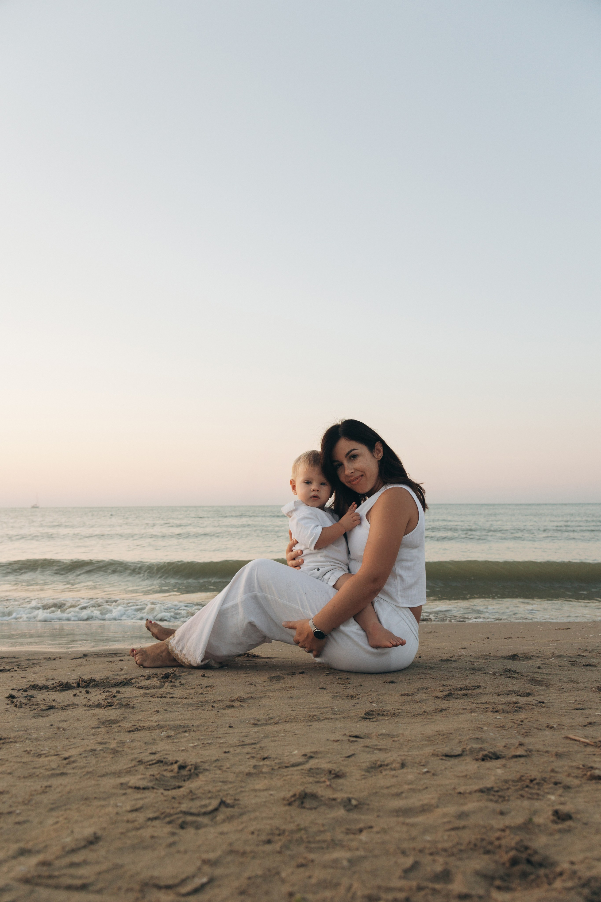 mamma seduta con bambino vicino al mare durante un servizio fotografico a Rimini