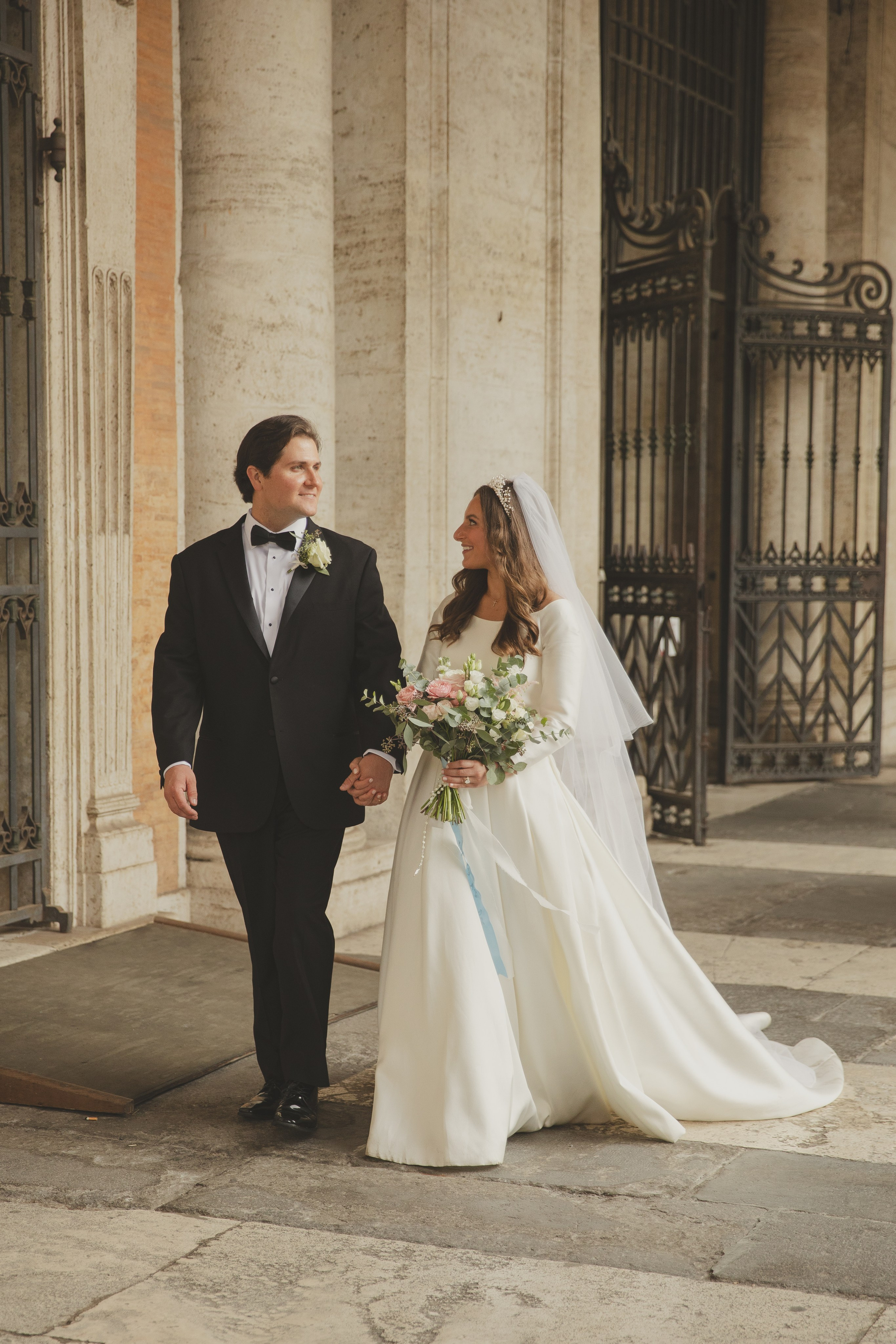 Newly married couple walking through the arcades of Piazza del Campidoglio in Rome.