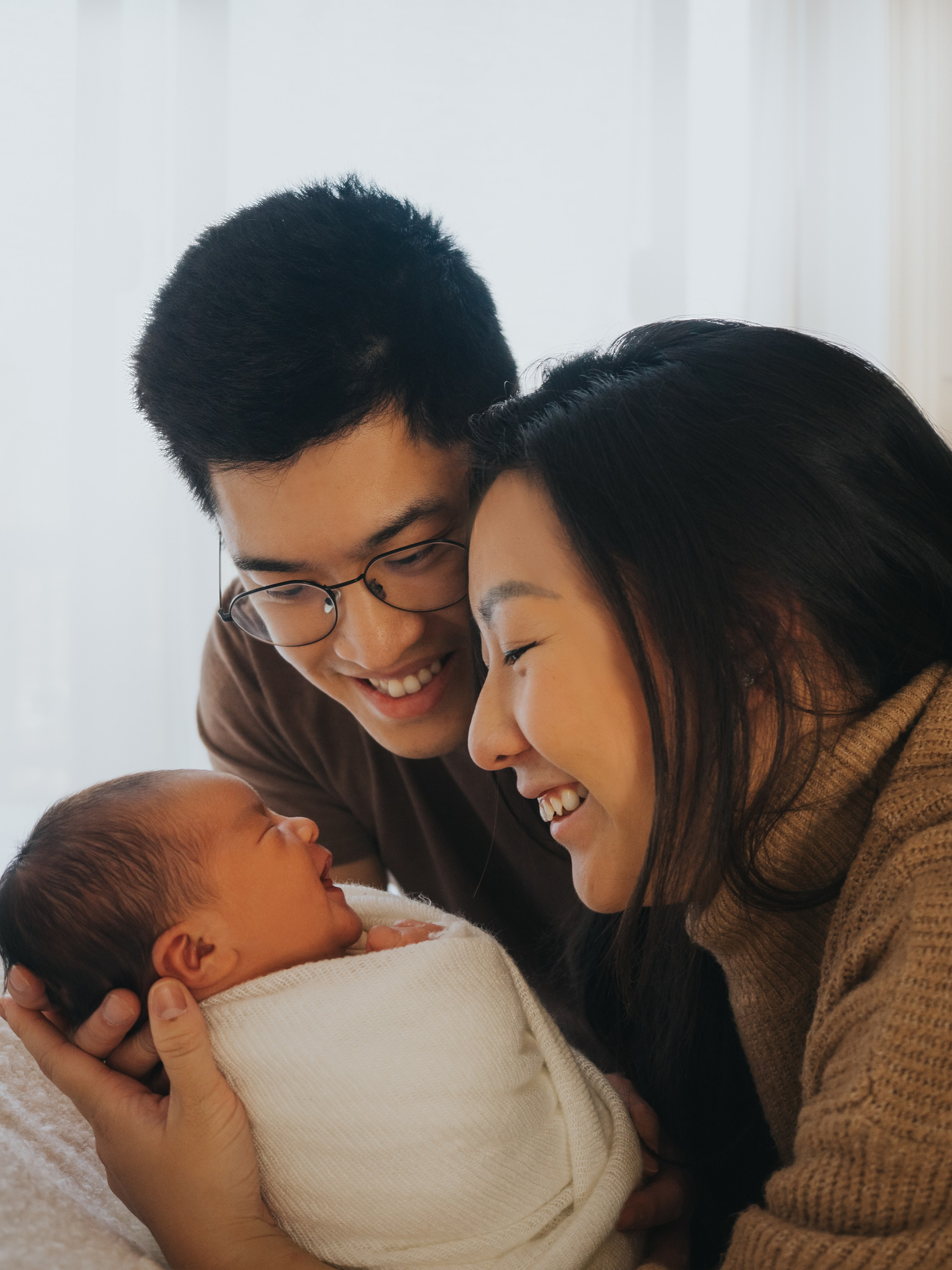 Parents smiling at their newborn baby.