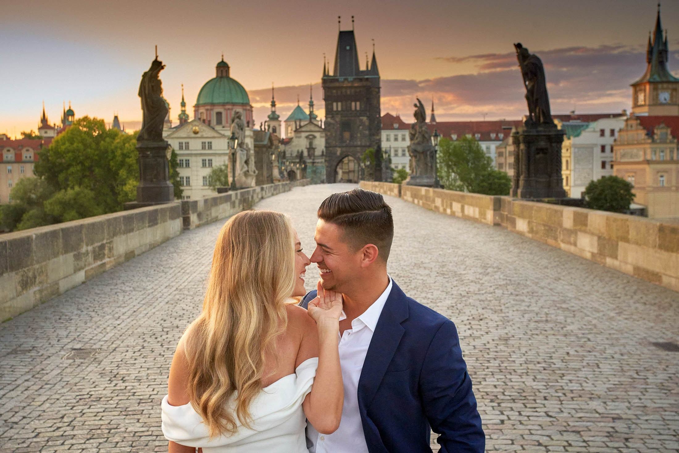 A romantic pair enjoying a solitary sunrise moment on historic Charles Bridge.