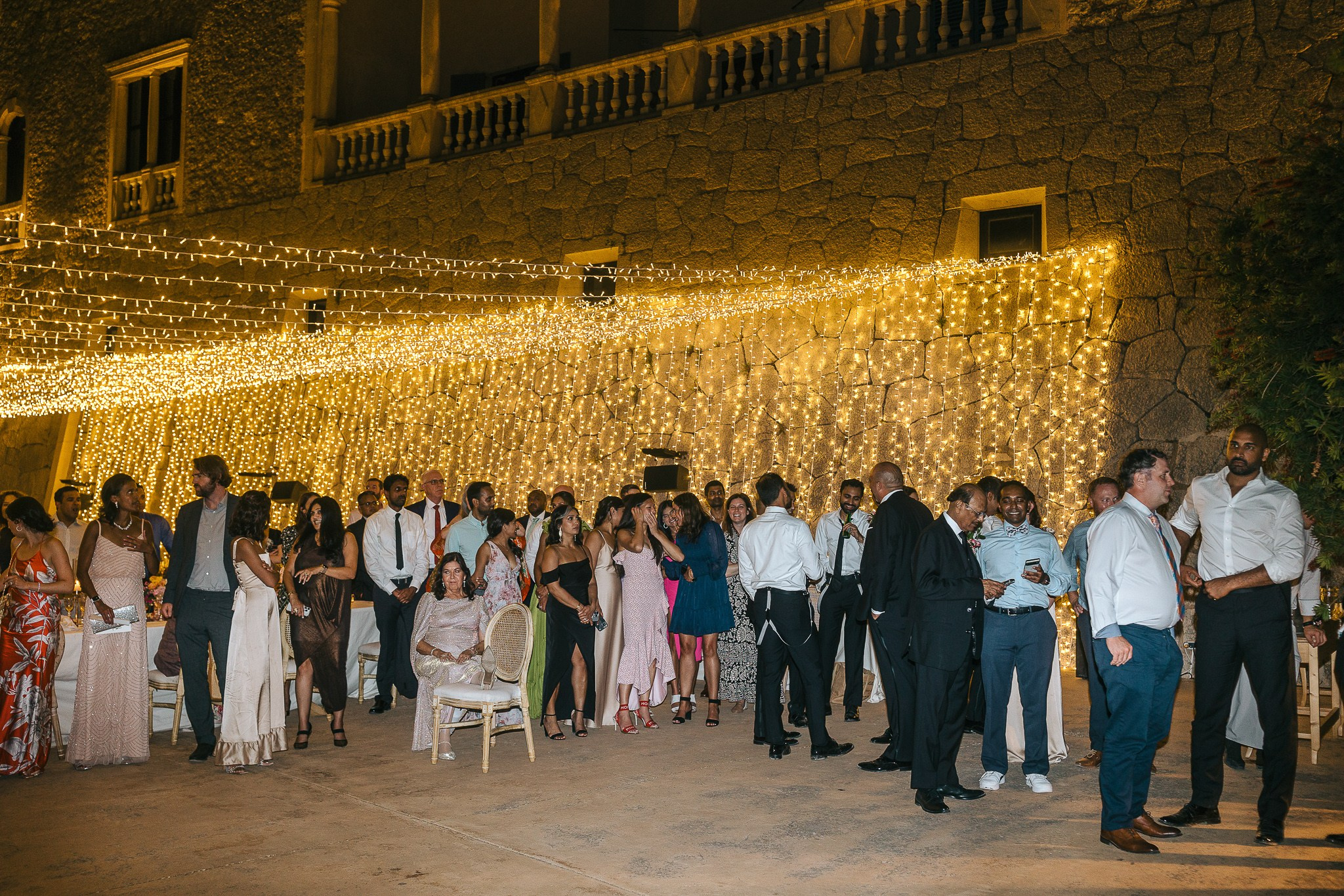 Wedding guests dancing and celebrating under string lights at a Mallorca wedding reception