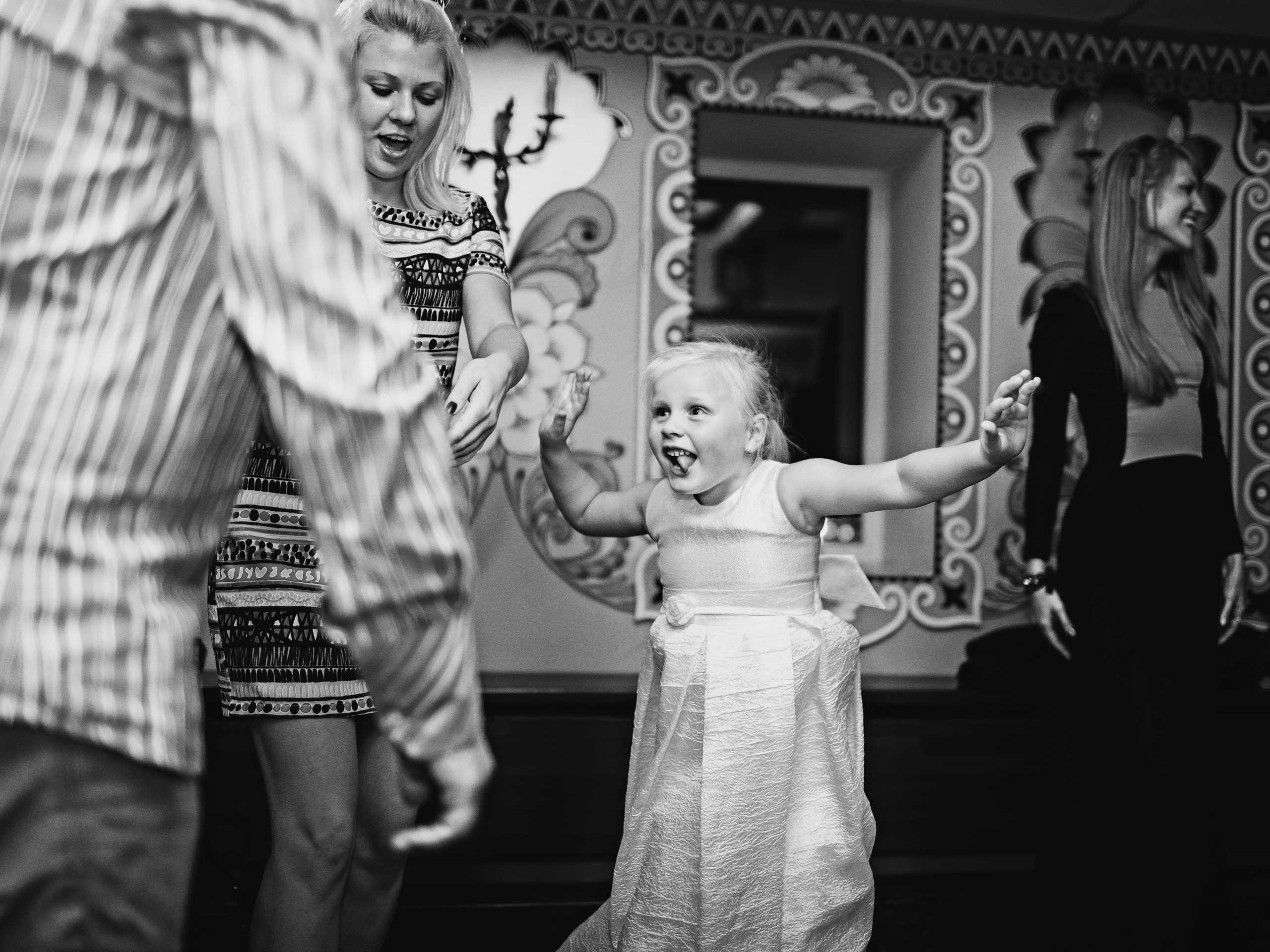 girl dancing and having fun among adults and showing the tongue