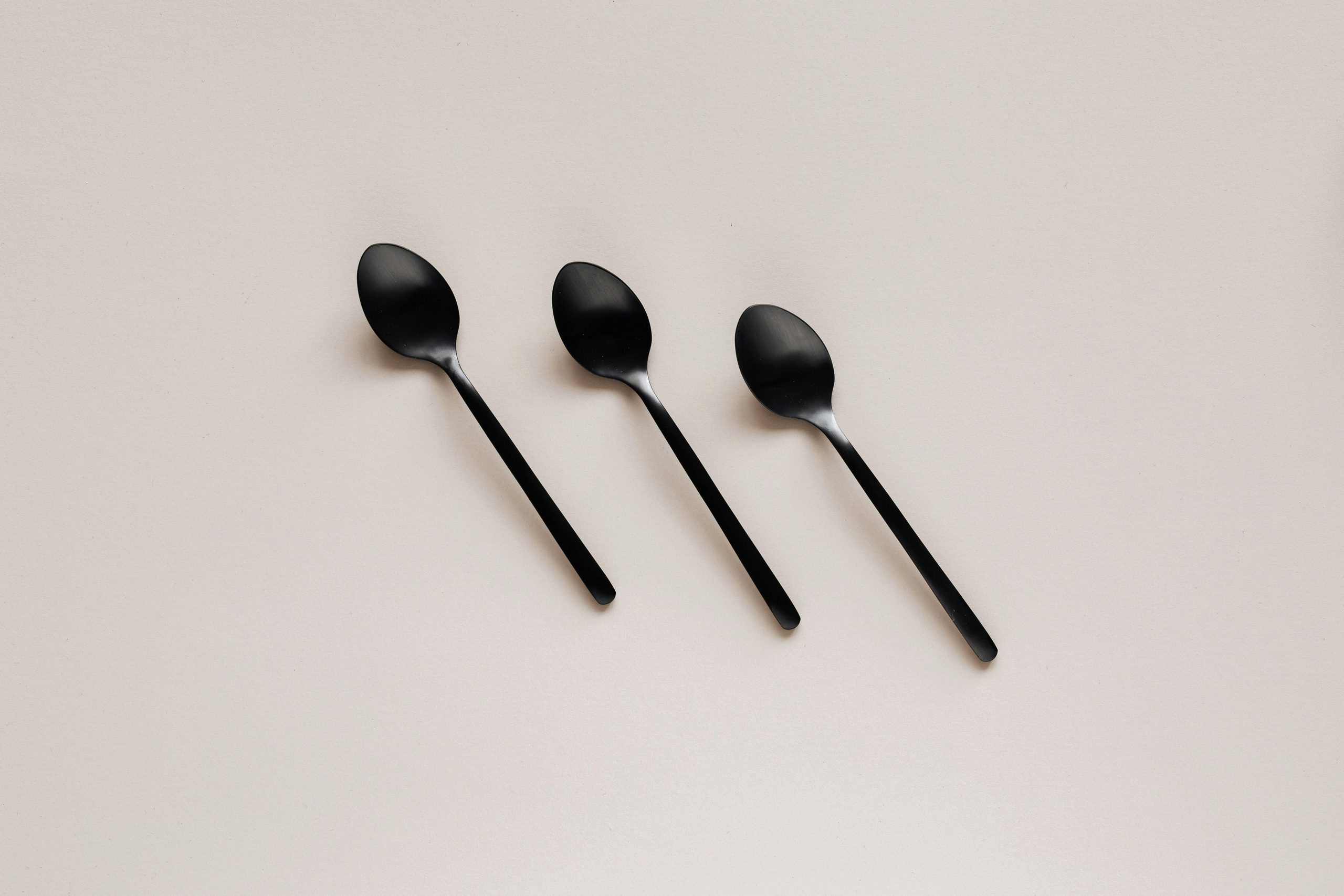 Modern flat-lay product photography of black spoons on white background, photographed by Jay Soundo Creative.