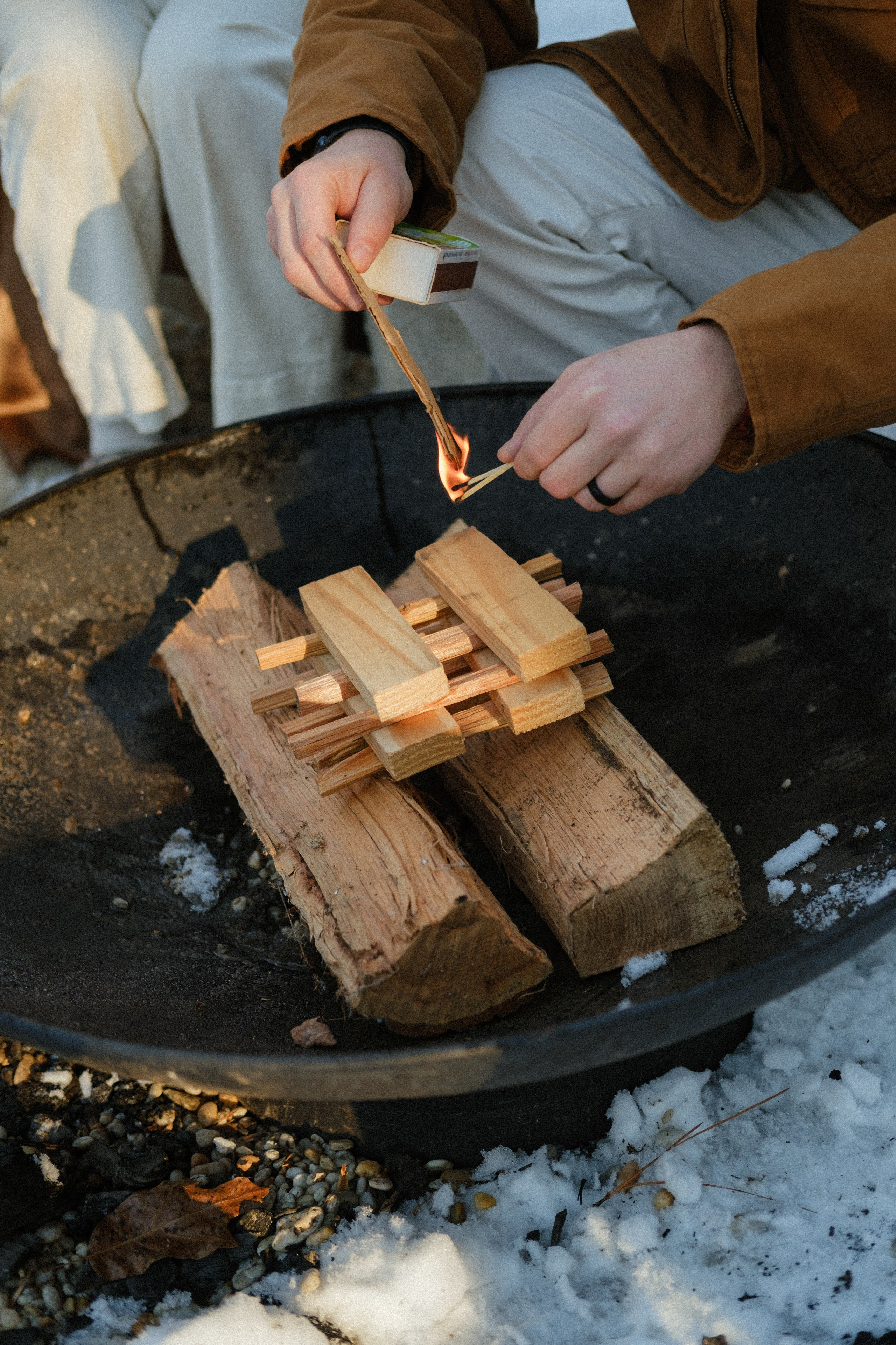 Dad lighting an outdoor fire for marshmallows in the snow near Richmond, VA — rustic family tradition captured beautifully.