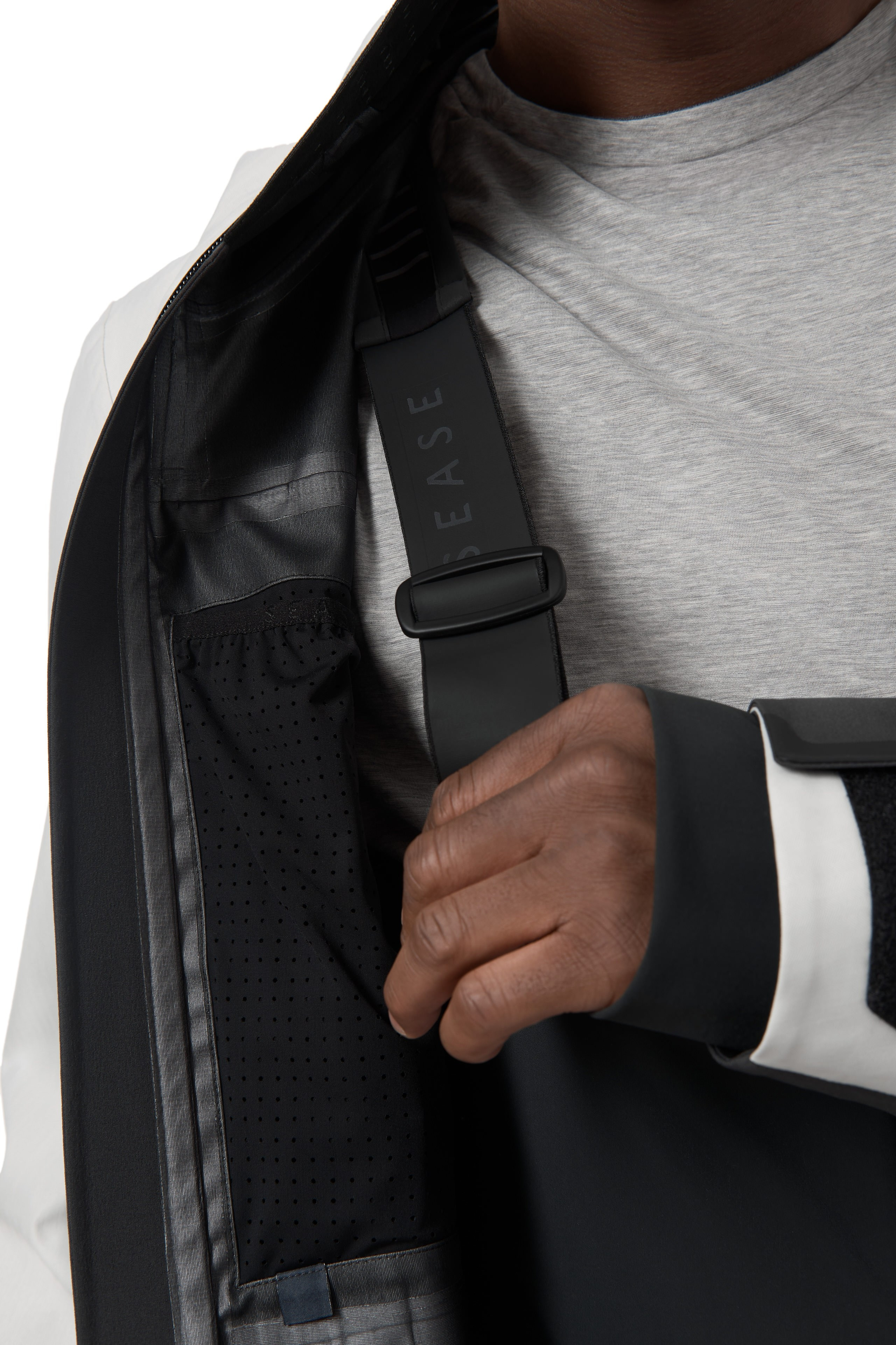 Detailaufnahme – Model öffnet Reißverschluss der schwarzen Jacke.