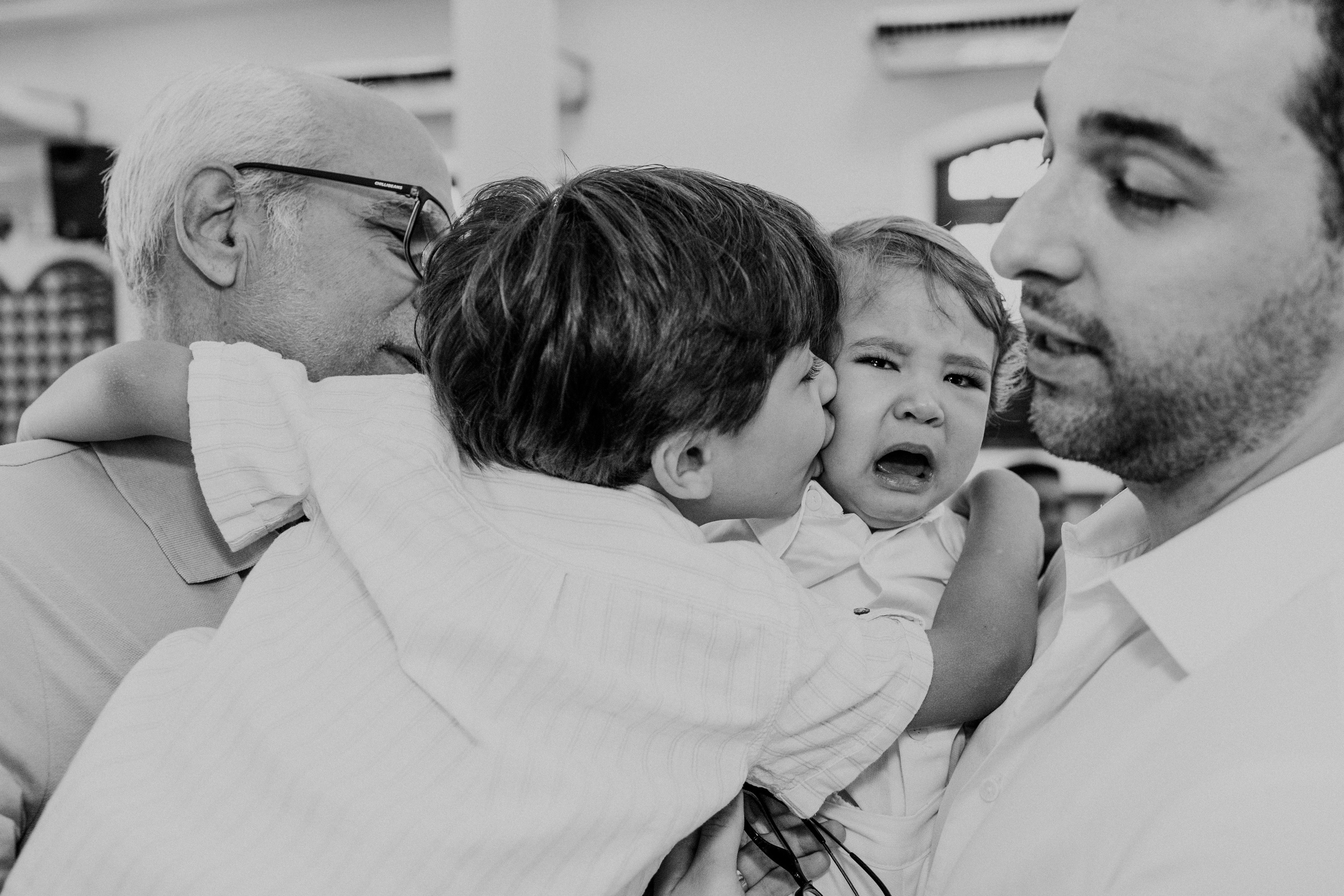 Abraço dos irmão em foto preto e branco, com bebê chorando