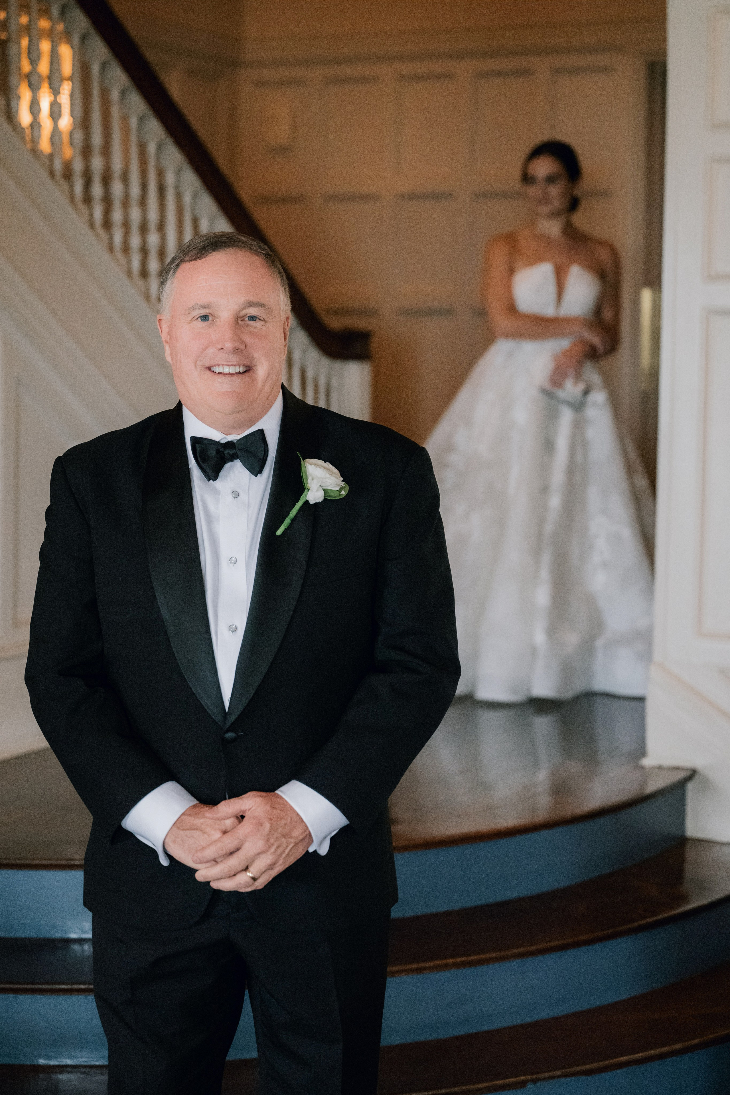 a man in a tuxed suit and bow tie standing on a staircase