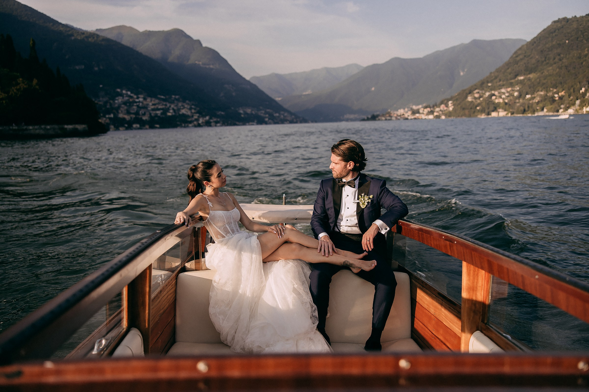 Bride and groom share an intimate moment on a boat, surrounded by calm waters.