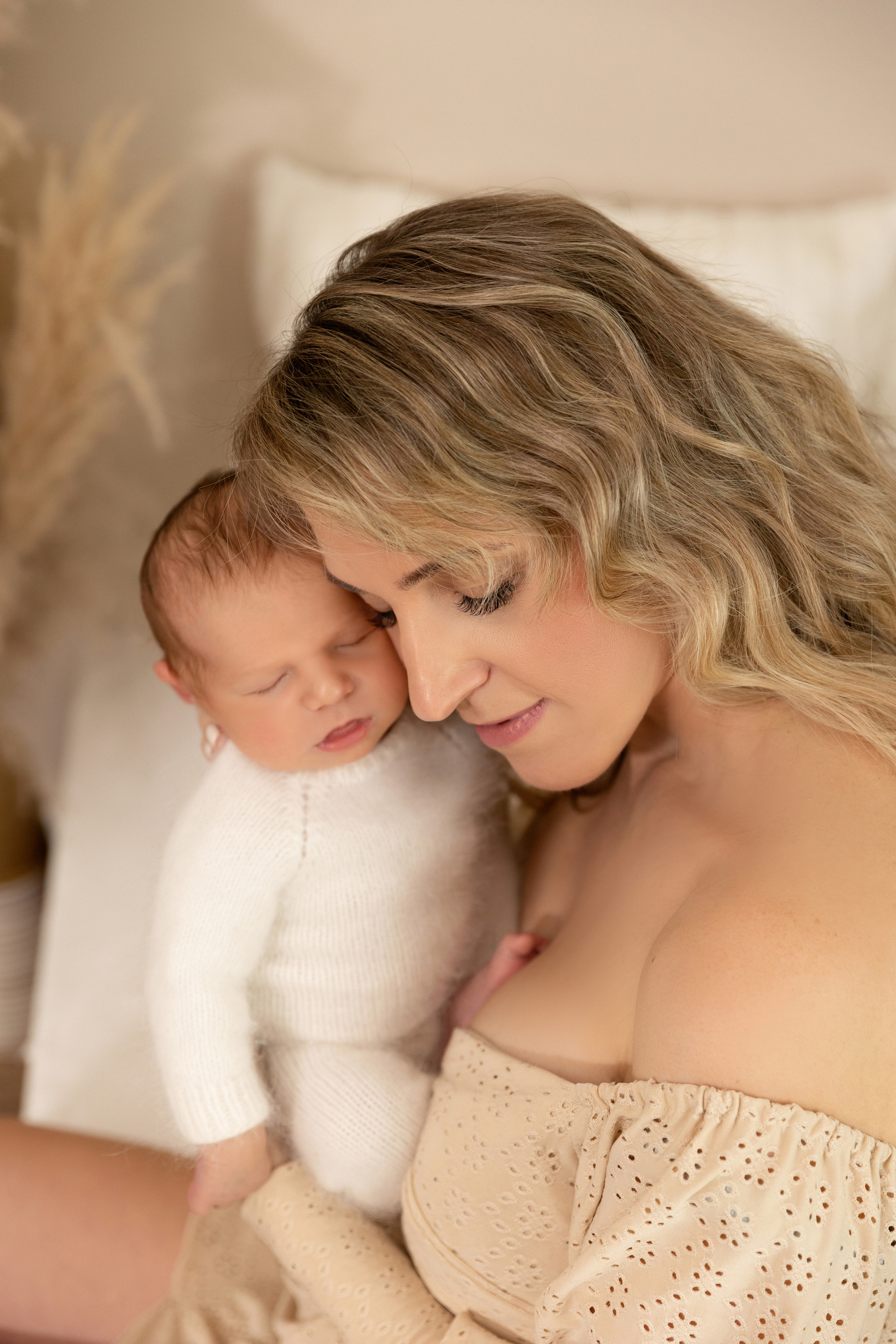 Emotionale Aufnahme einer Mutter, die ihr Neugeborenes liebevoll küsst – Babyfotoshooting in Iserlohn.