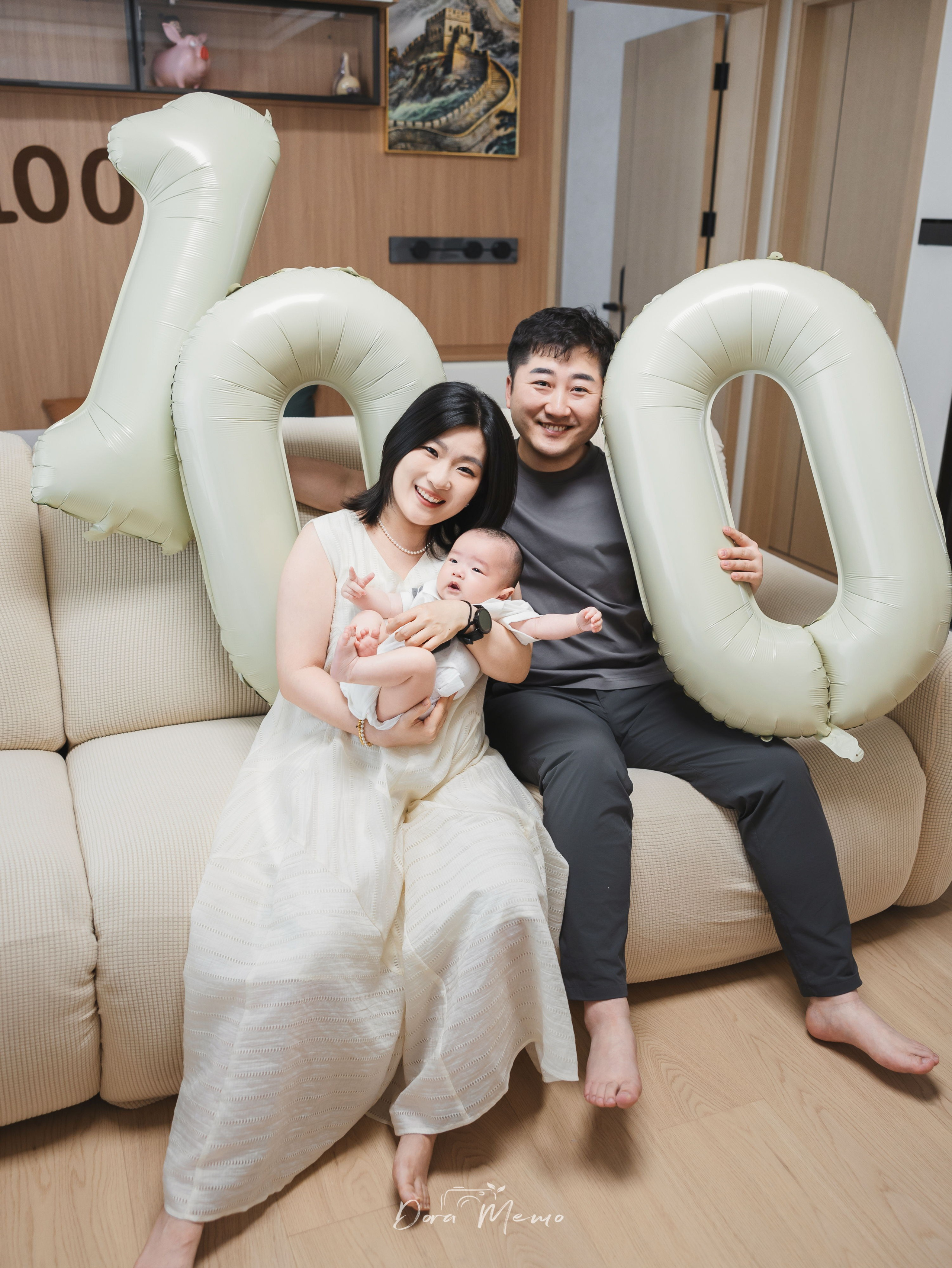Parents sitting with their 100-day-old baby in their newly renovated home for a simple family portrait.