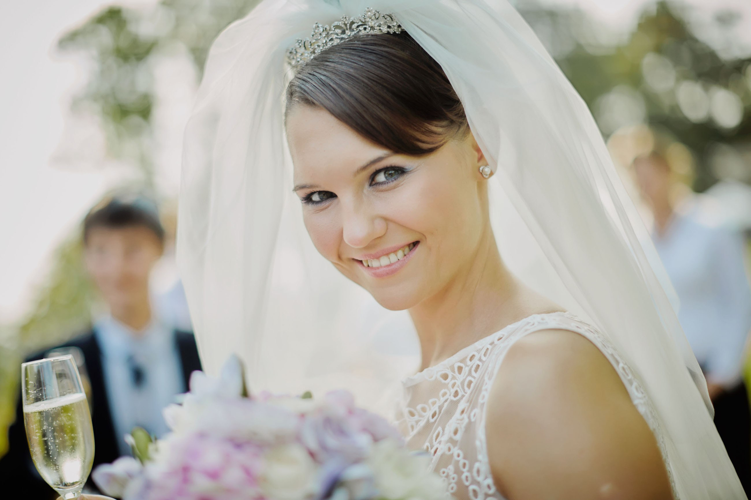 Radiant bride with champagne and bouquet at chateau after garden wedding