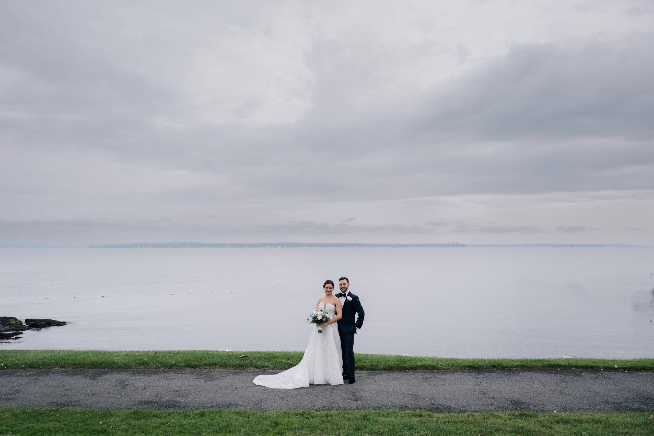 a bride and groom pose for a photo on the shore of lake michigan