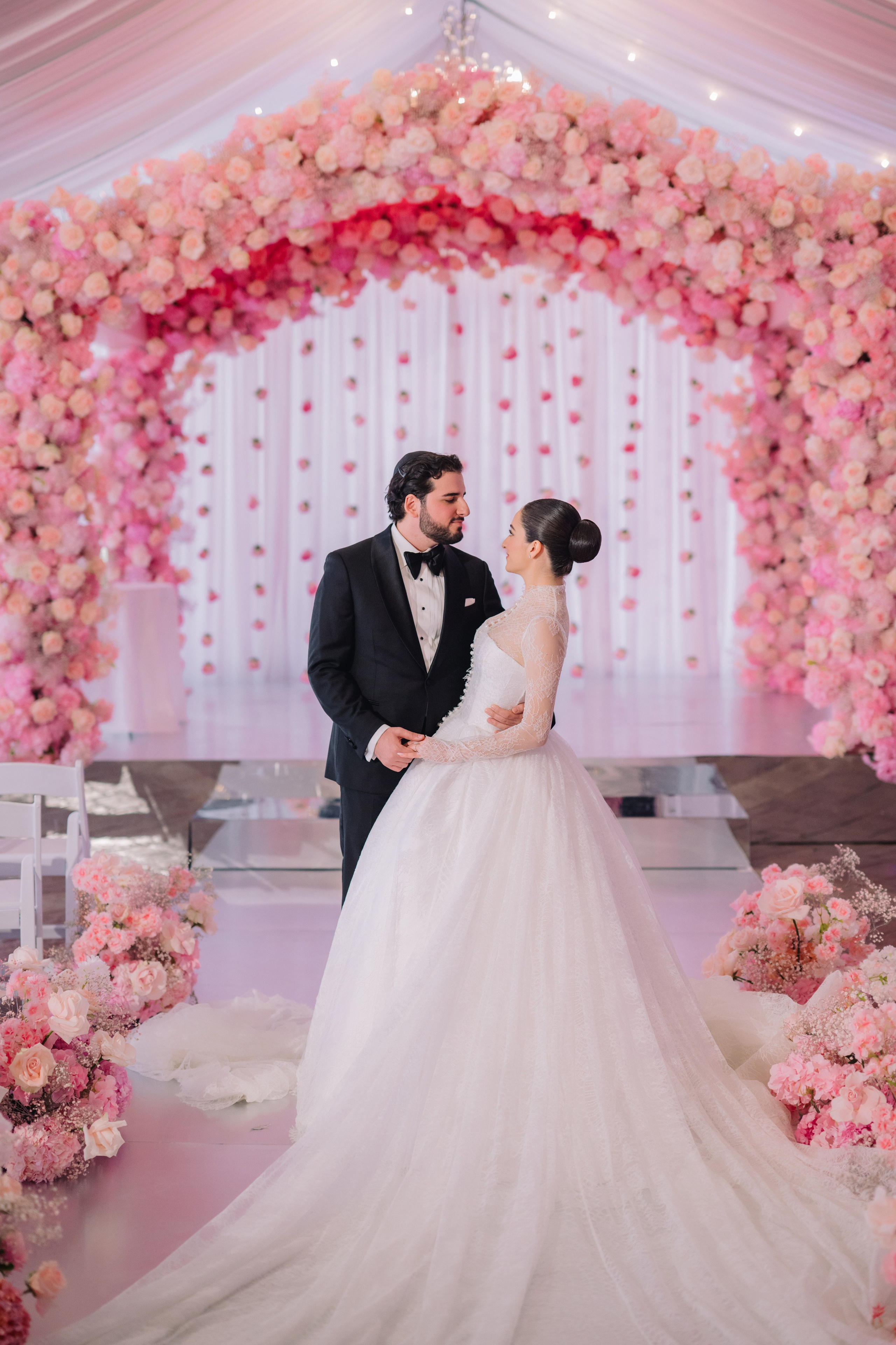 a bride and groom standing in front of a floral arch