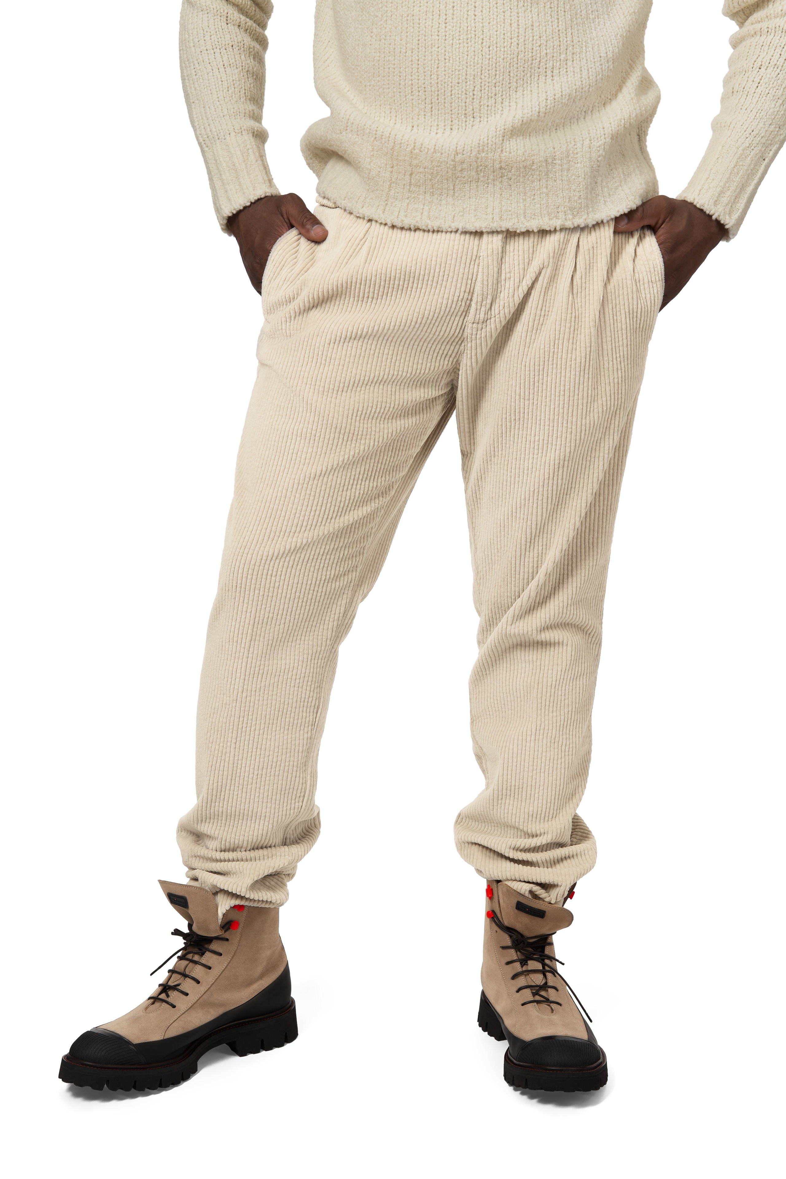 Detailaufnahme – Model im kompletten Outfit aus Strickpullover und Cordhose in Beige, stehende Pose.