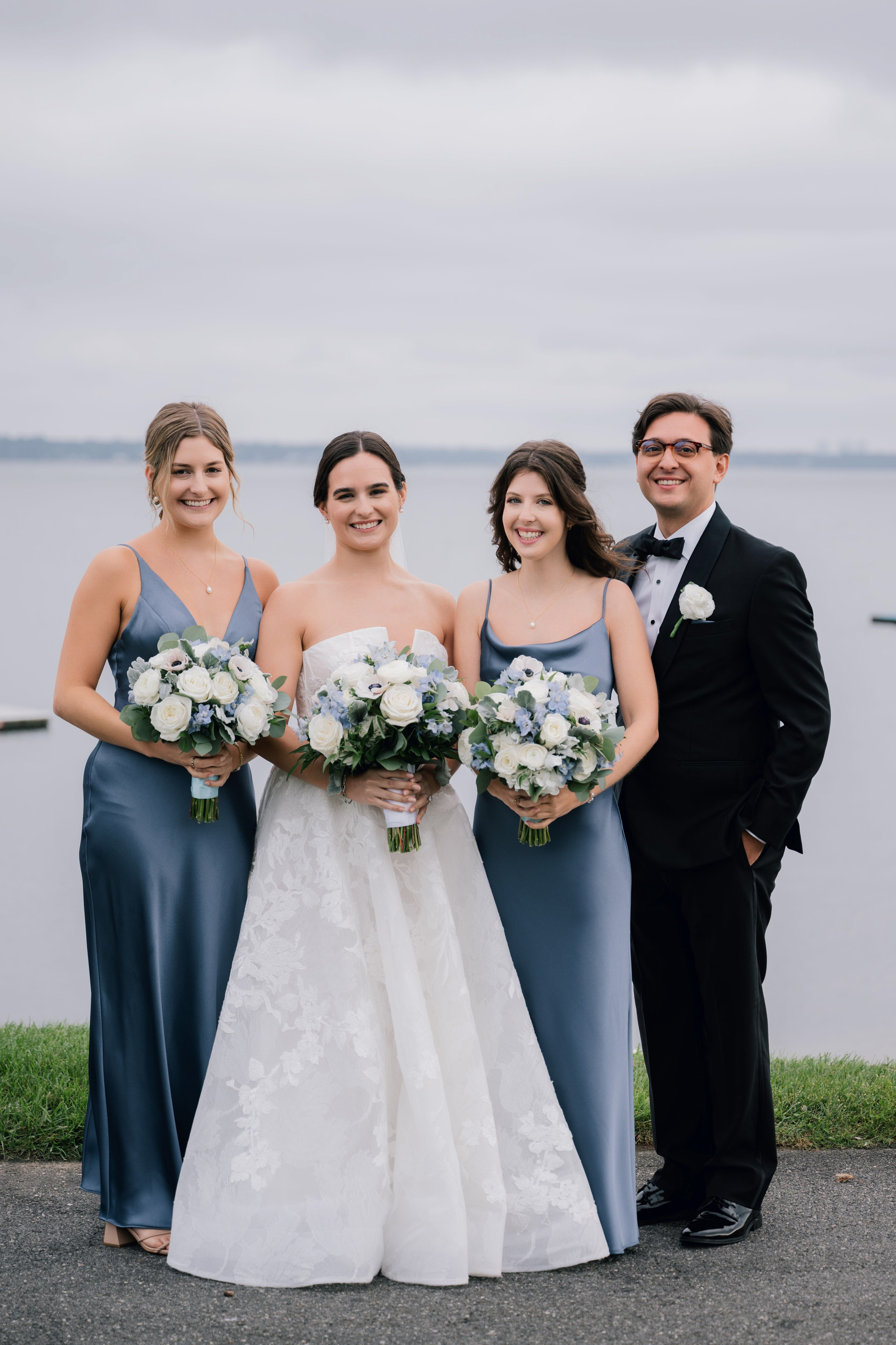 a bride and her bridesmas pose for a photo in front of the water