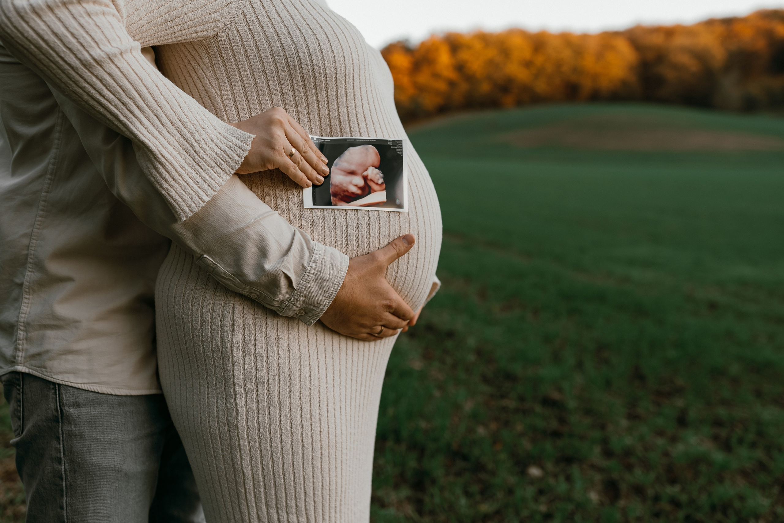 Familienglück. Schwangere Frau zeigt stolz ihren Babybauch und das Ultraschallbild