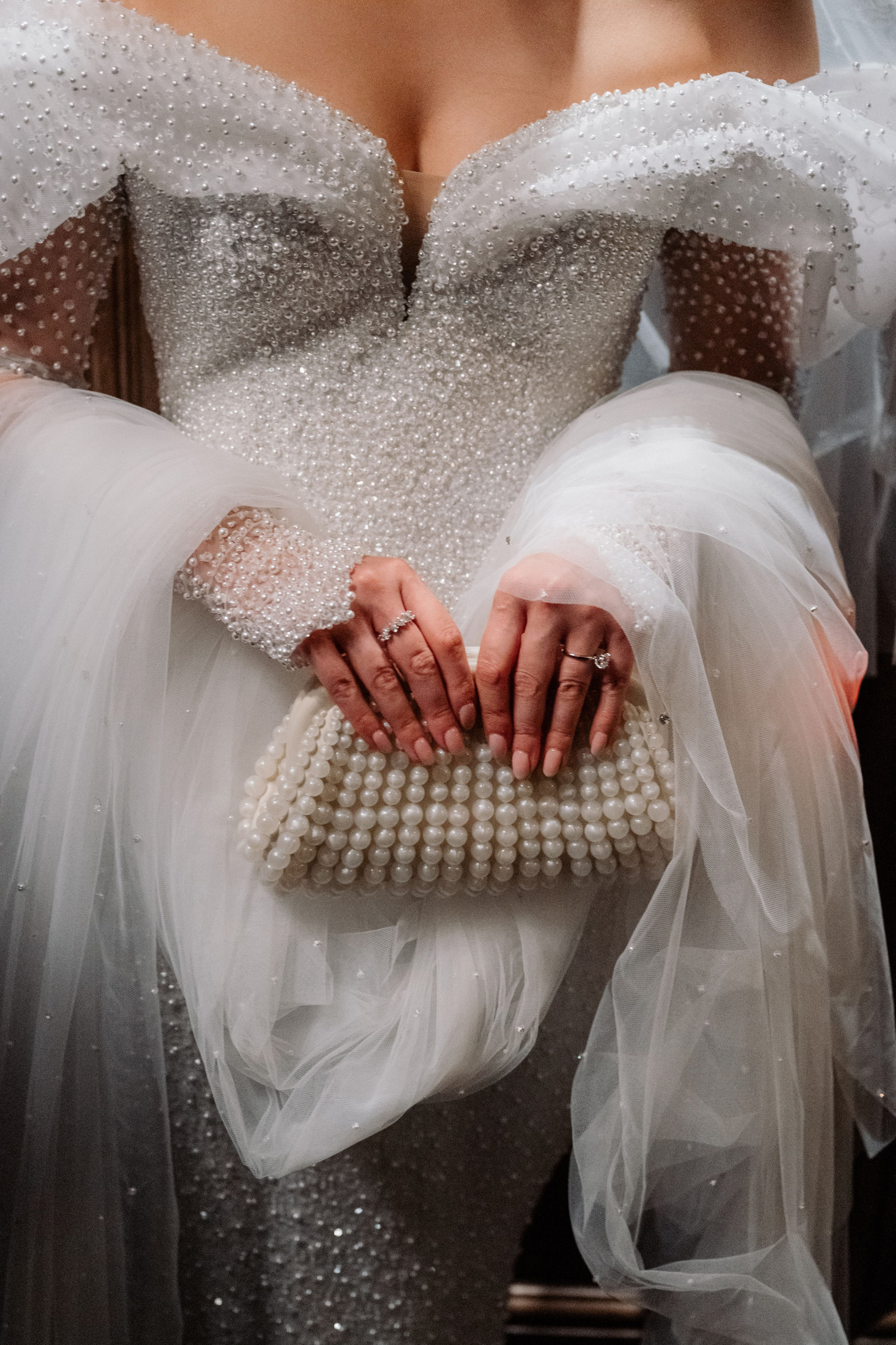 a woman in a wedding dress holding a pearled clutch