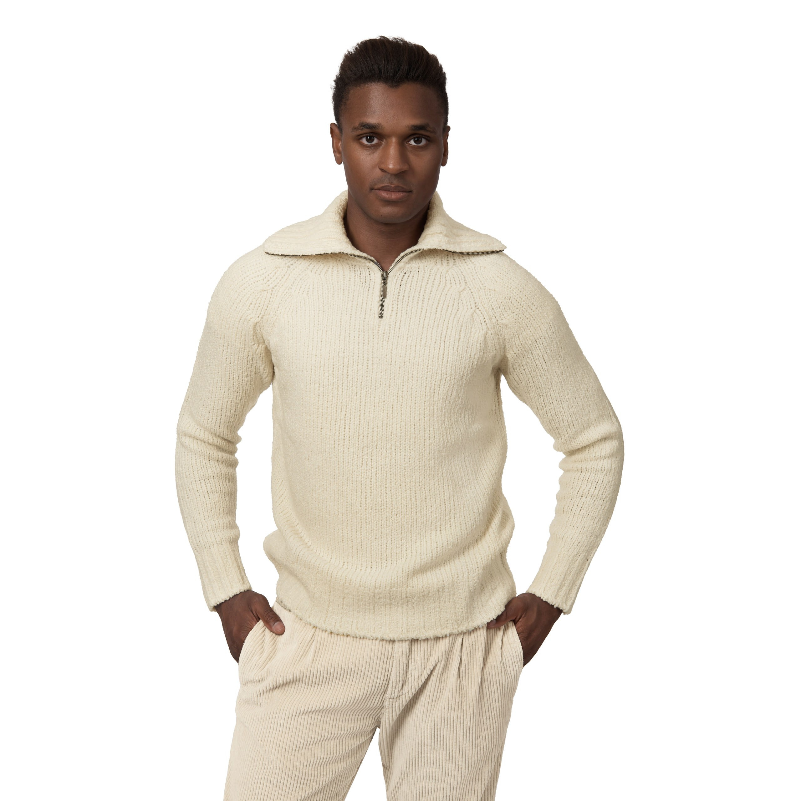 Männliches Model in cremefarbenem Strickpullover mit halbem Reißverschluss und Cordhose, Studioaufnahme.