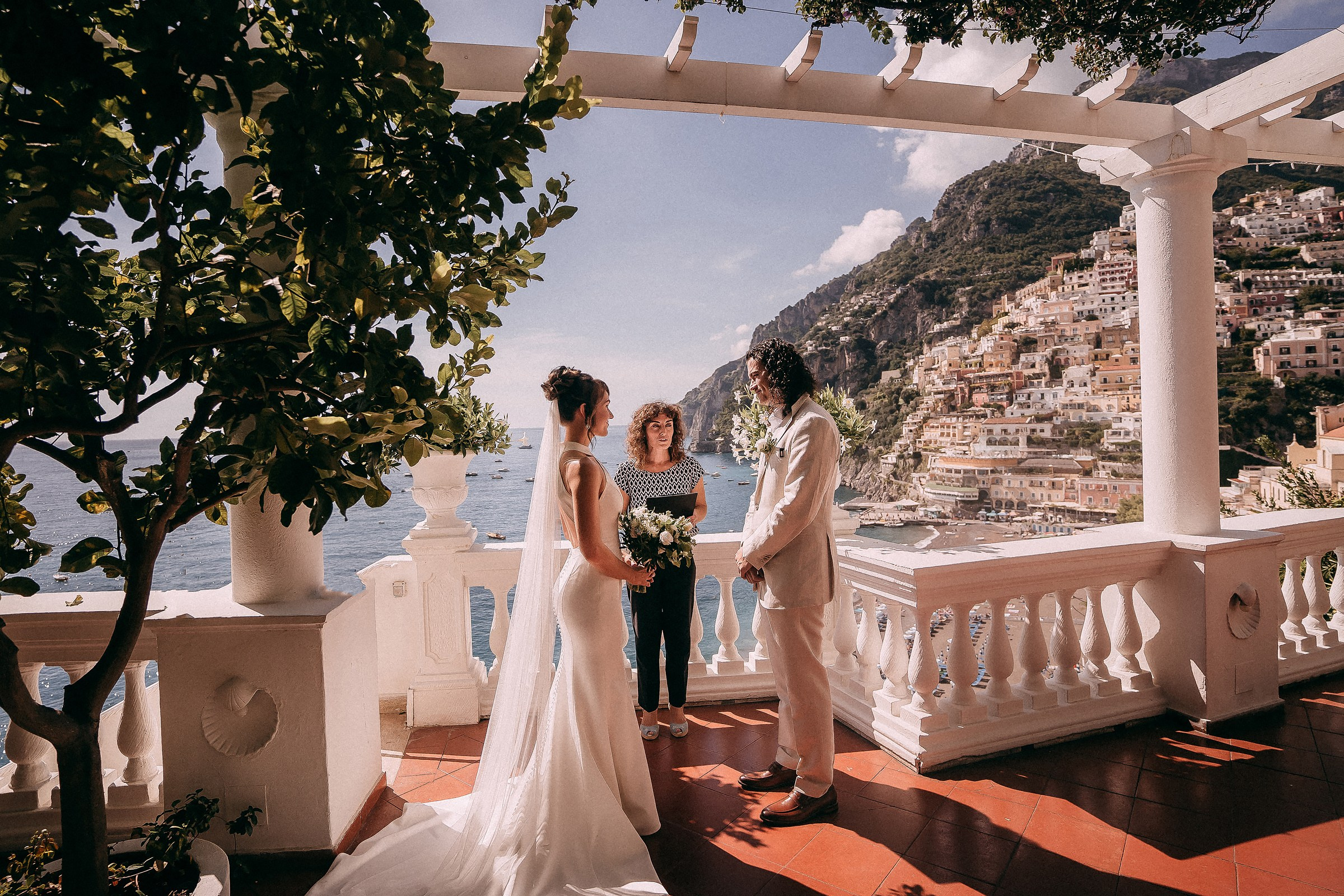 The bride and groom exchange vows on the terrace of Villa Boheme, with the stunning backdrop of Positano’s iconic colorful buildings and serene ocean views.