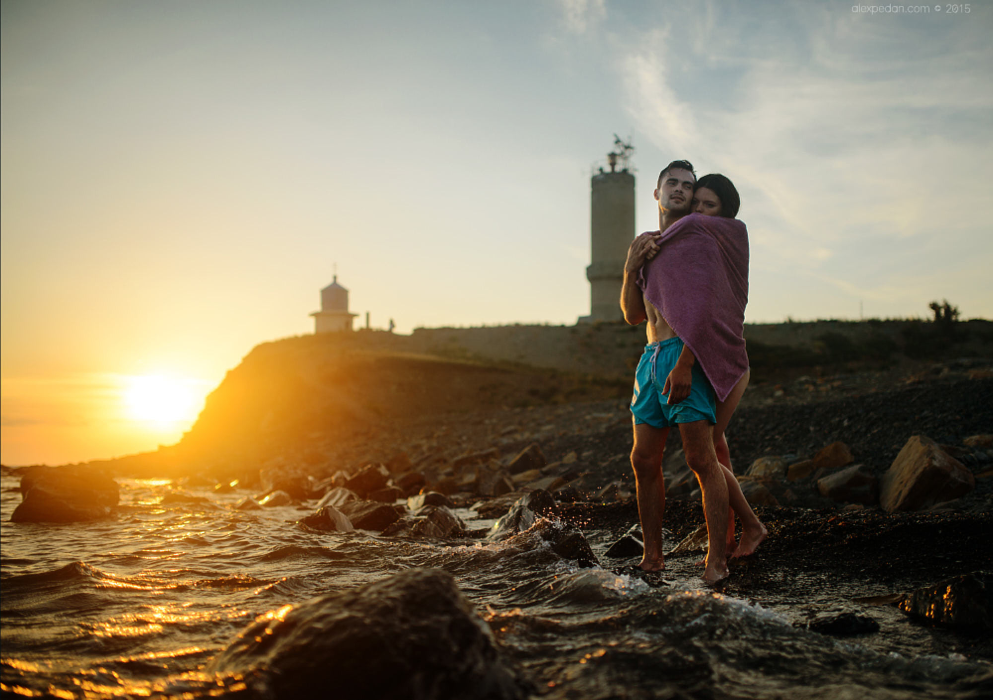 Intimate beach engagement photoshoot of a couple cuddling under a towel to keep warm, in Montauk, NY.