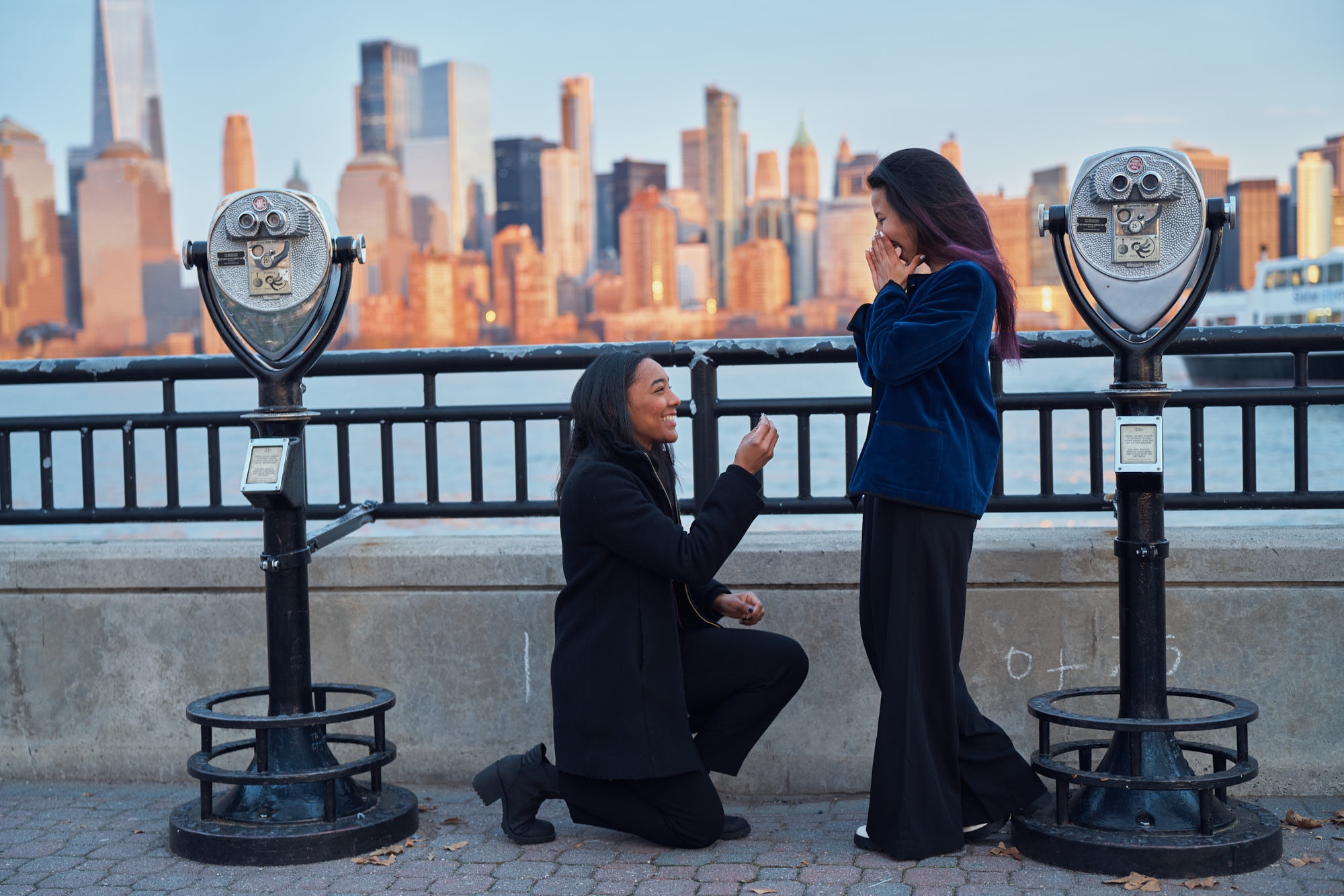 Secret proposal of same gender female couple. Shot during sunset in Liberty State Park, Jersey CIty, NJ with iconic Manhattan skyline as a backdrop.