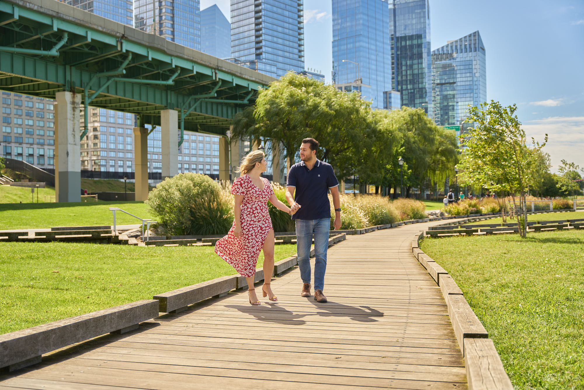 Sunny colorfull engagement photo of Chelsea and Steve walking down Riverside Park South, New York,