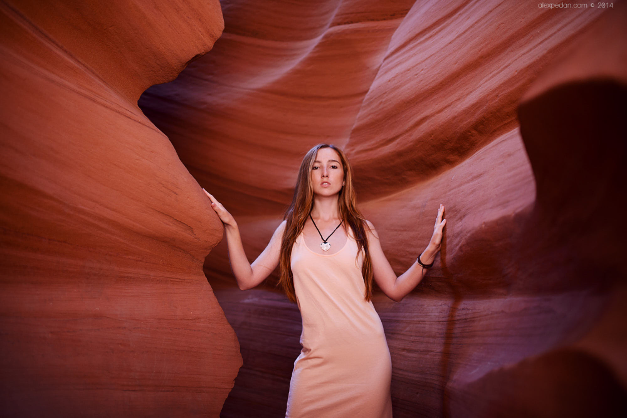 Beautiful editorial model in pink dress in red rocks of Upper Antelope Canyon, AZ.